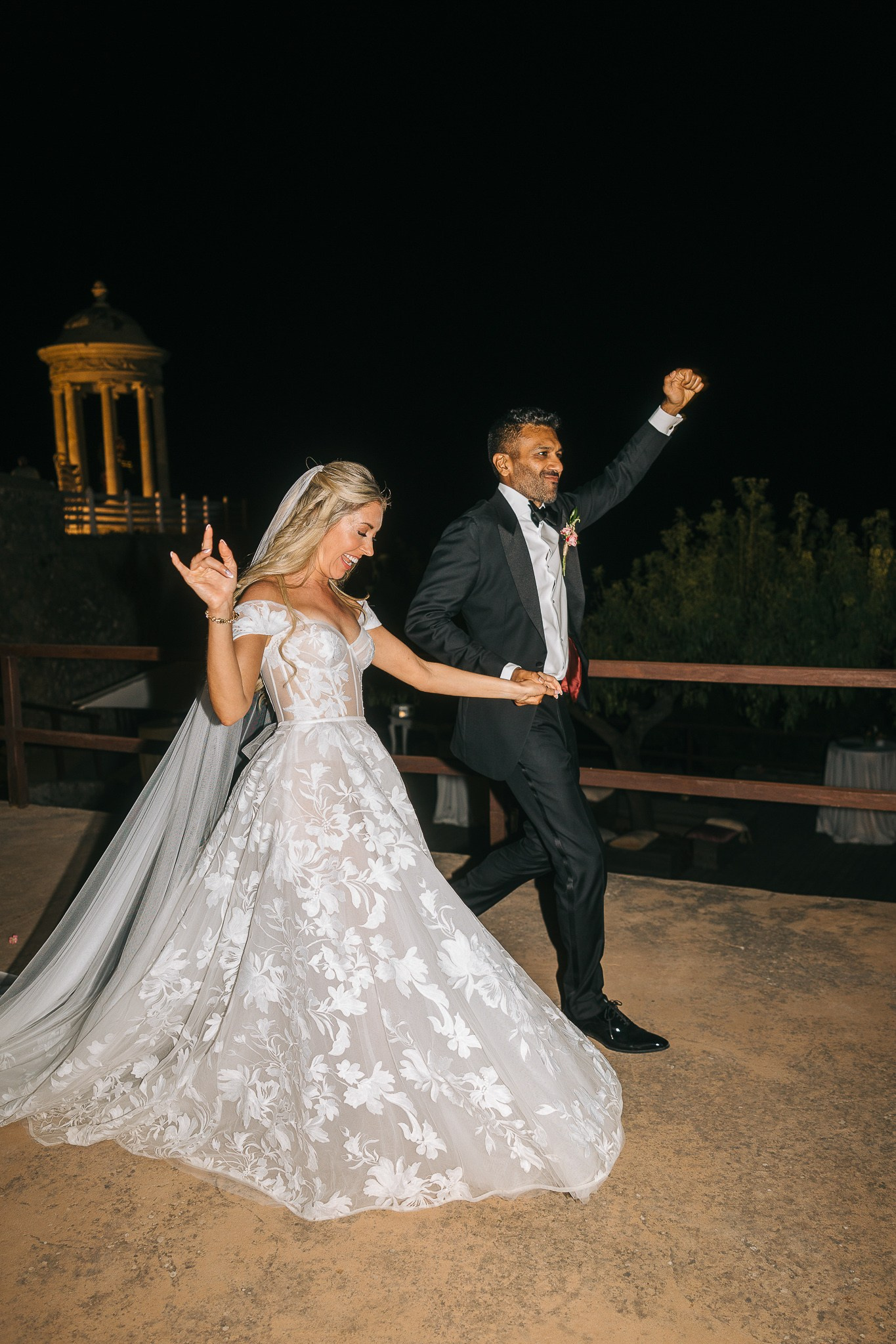 Bride and groom laughing together at their reception table lit by string lights, Mallorca weddin