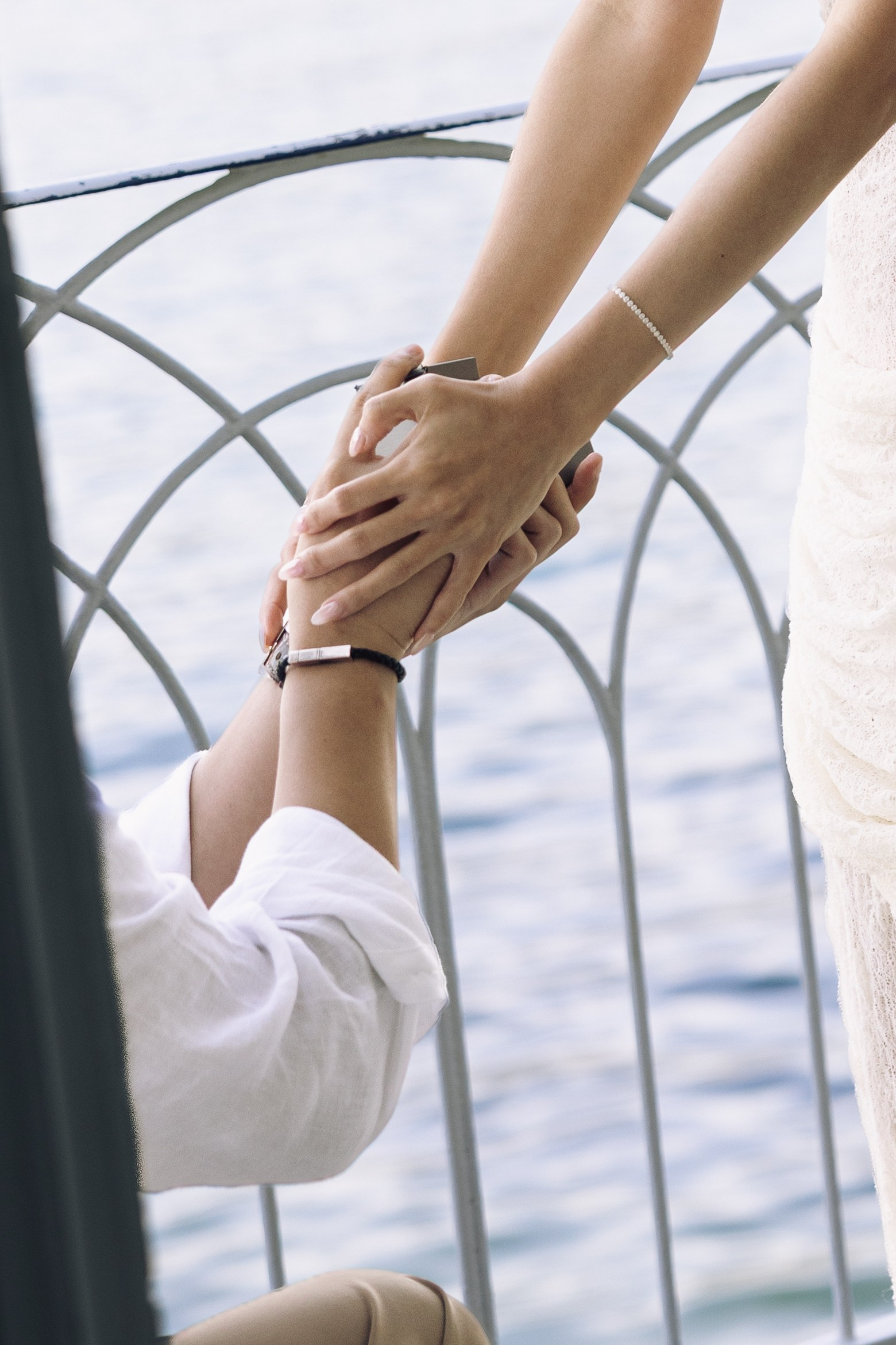 Close-up of a couple holding hands during a marriage proposal overlooking Lake Como