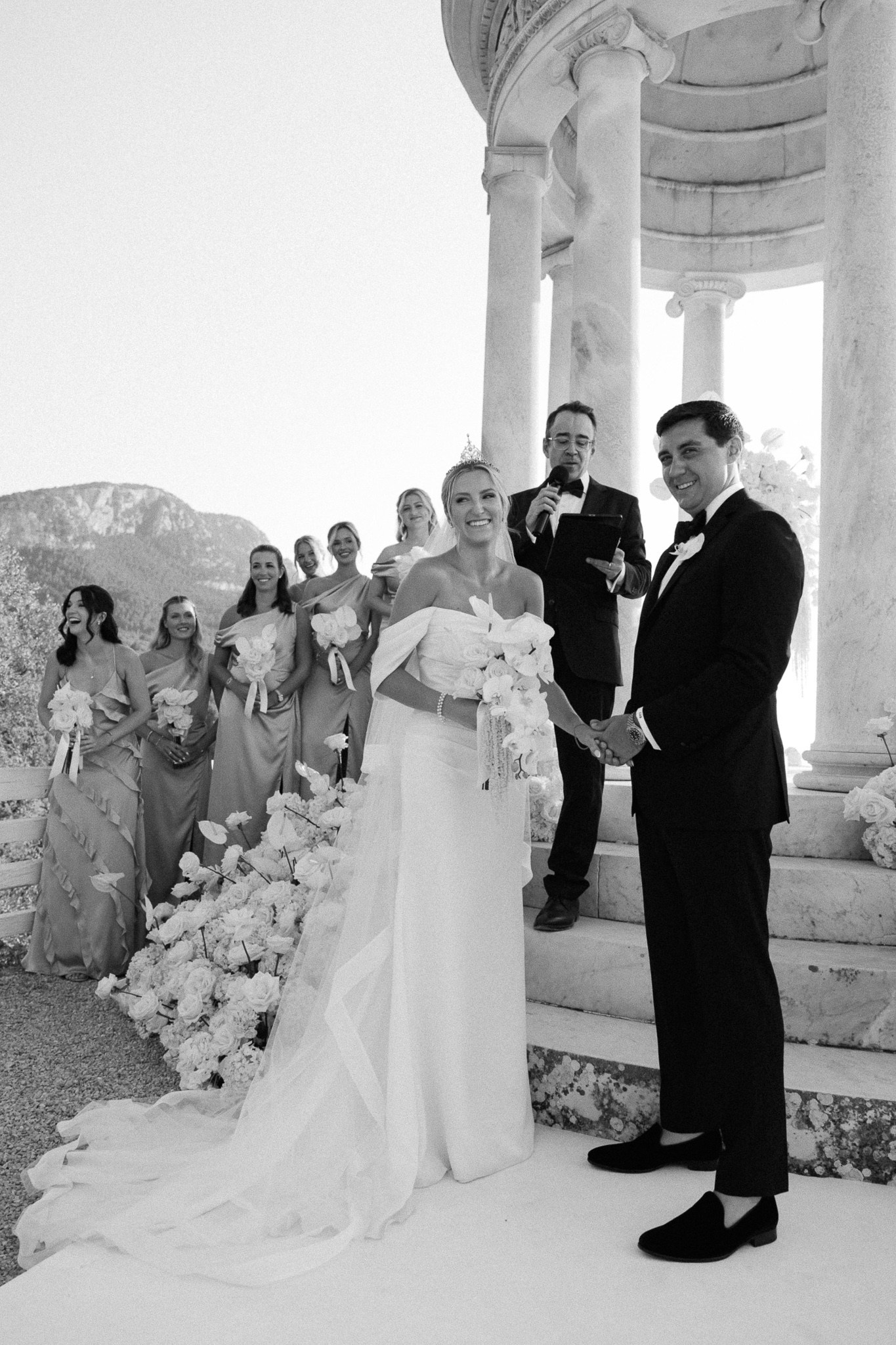 Black and white photo of bride and groom laughing with their wedding officiant at Son Marroig