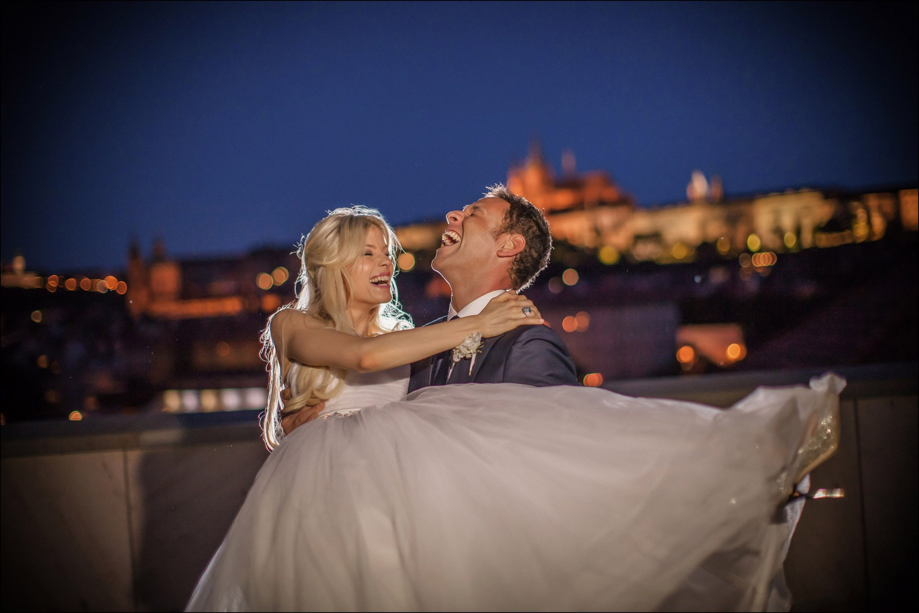 Laughing newlyweds groom holding bride night atmosphere Prague