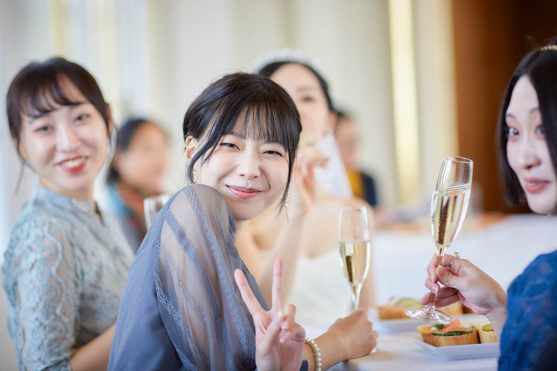 Bride and friend gesturing happily with champagne at reception.