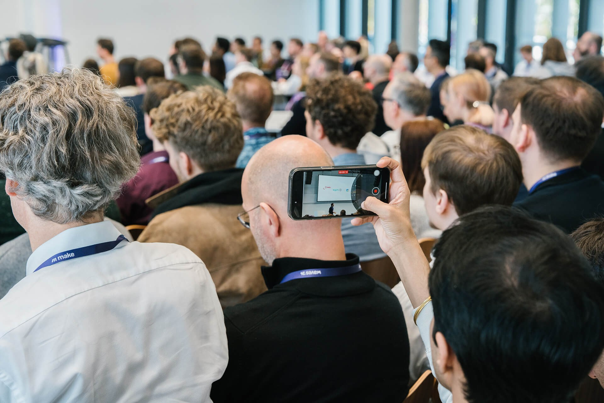 Teilnehmende machen Smartphone-Fotos während einer Live-Präsentation