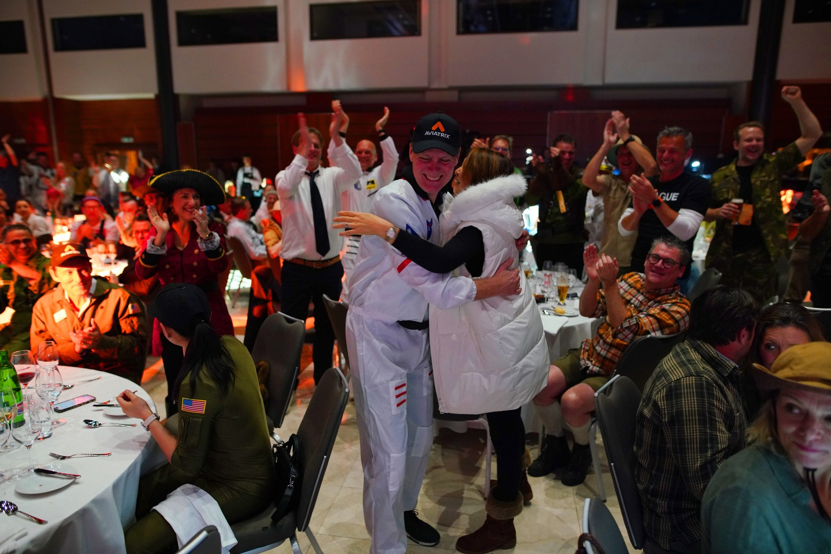 Award recipient embraced by team with standing ovation at Orange Business adventure-themed gala 2026 Hilton Prague.