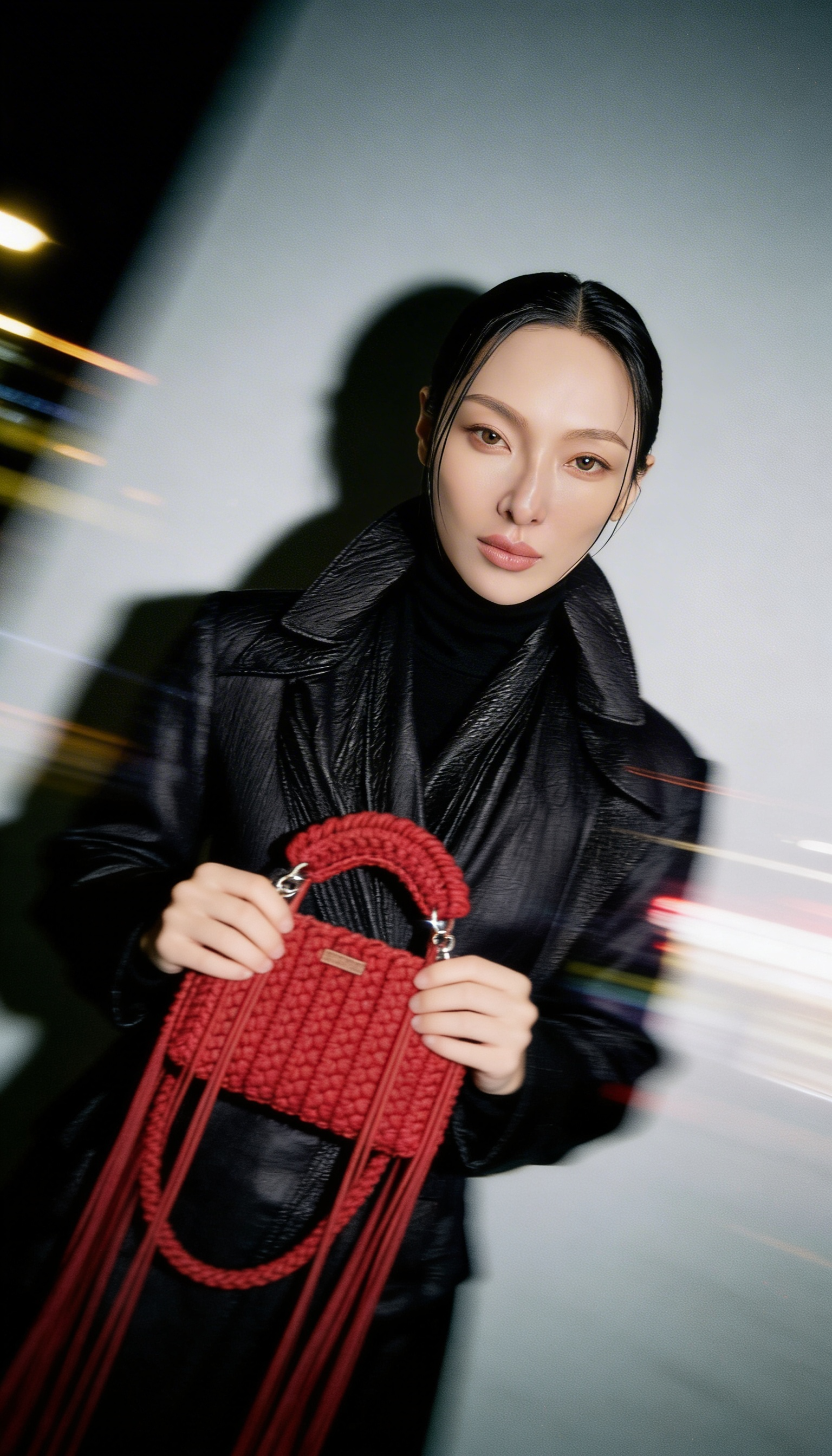 Fashion model in black coat holding red macramé handbag with dynamic light streaks, cinematic editorial fashion photography