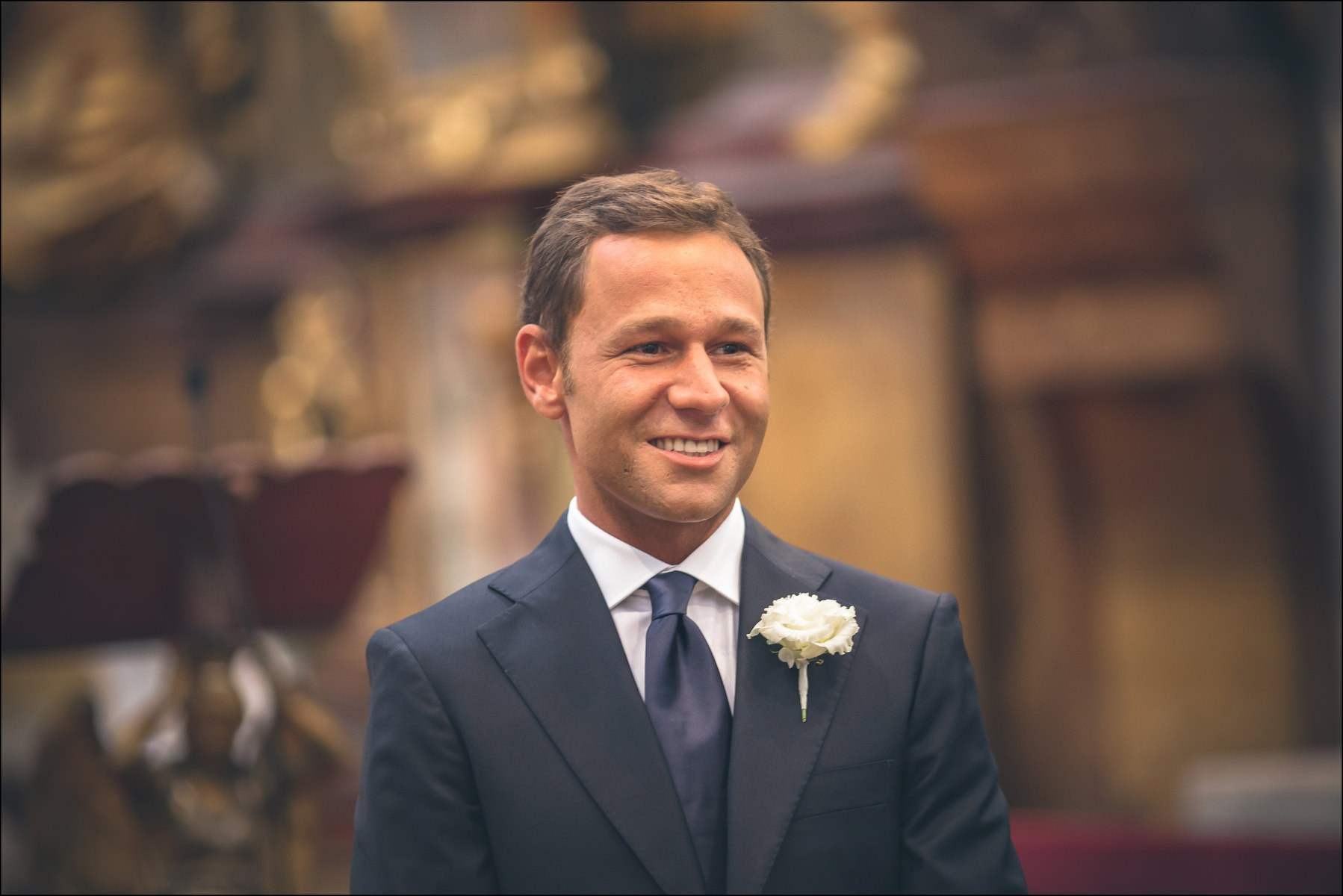 Groom Sergio smiling at altar during ceremony at St. Thomas Church Prague