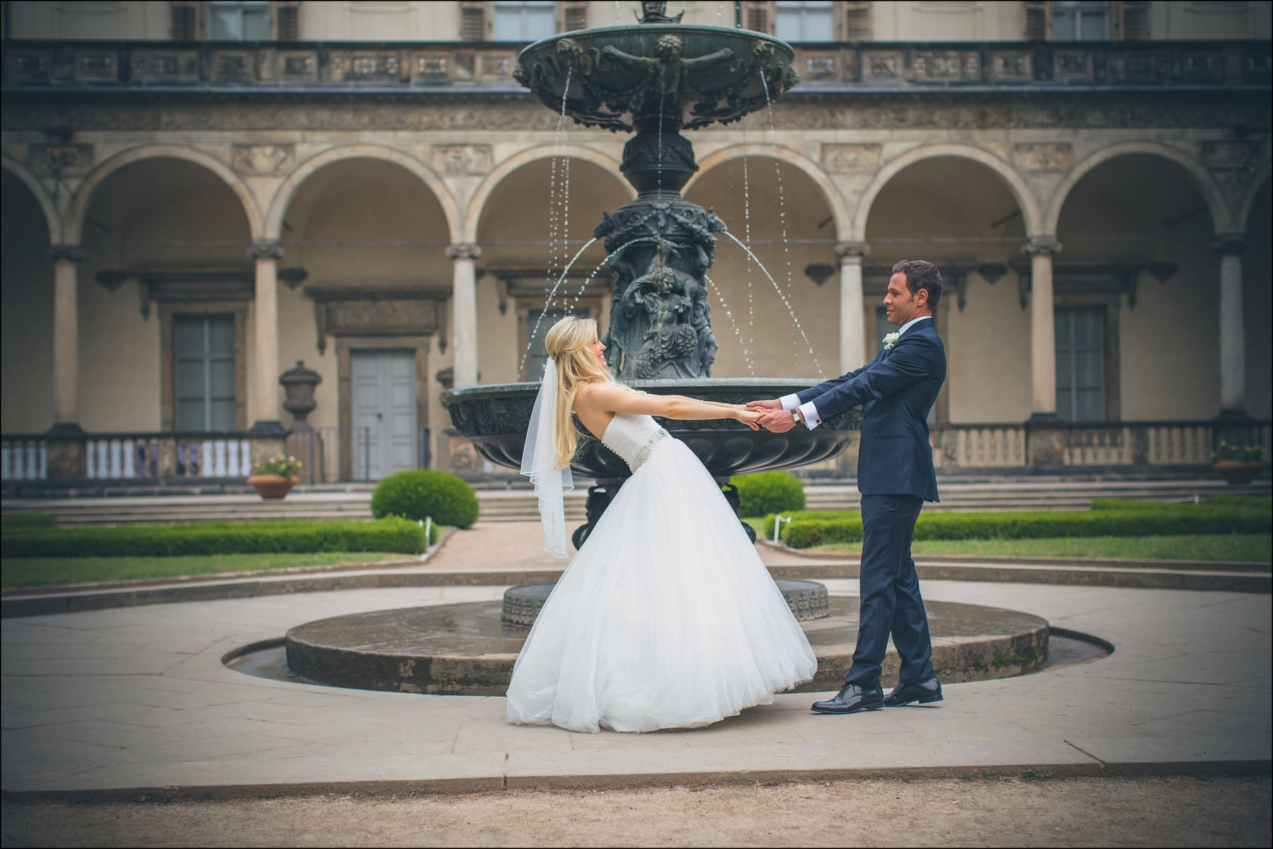 Playful embrace near historic fountain Queen Anne's Palace Prague