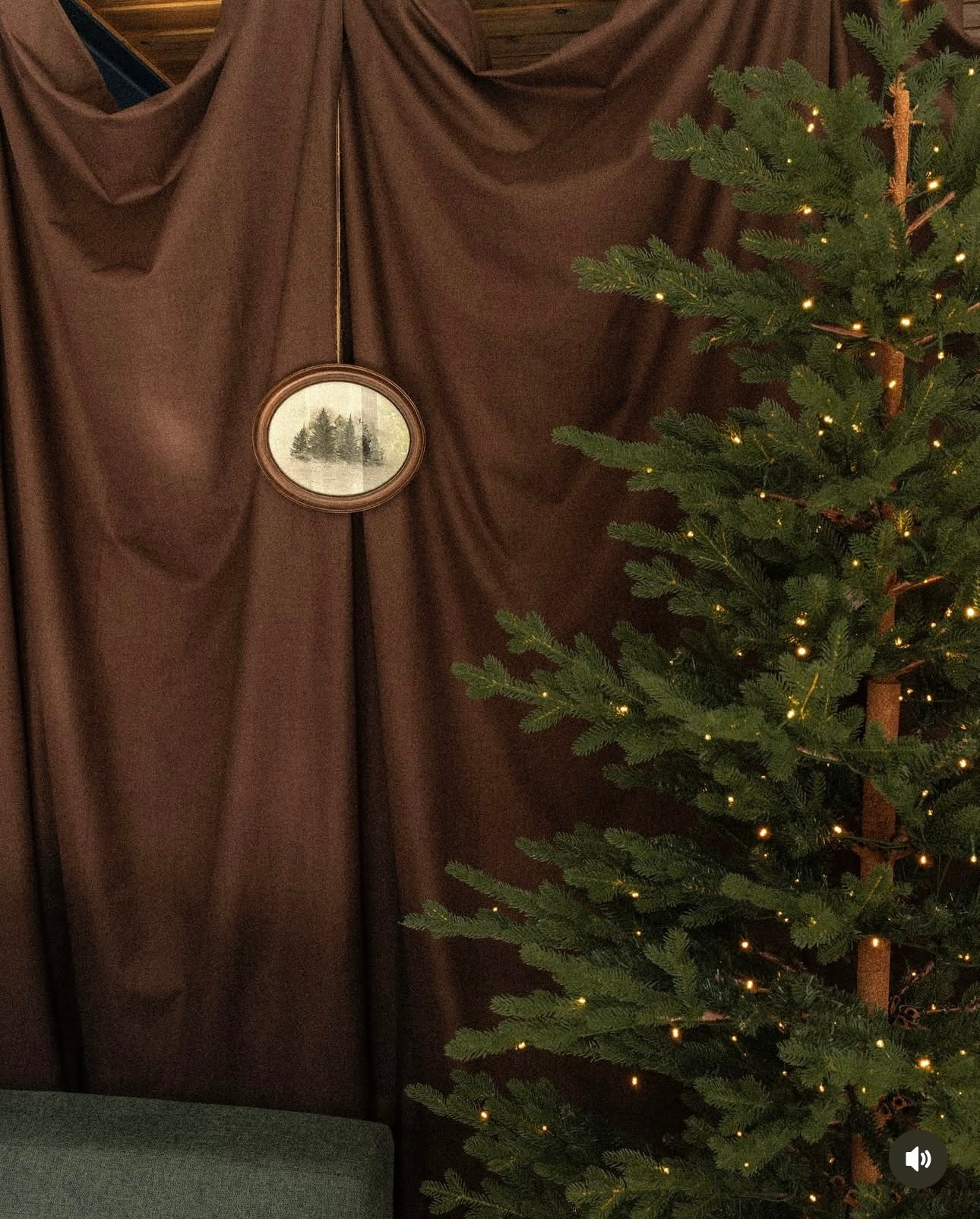 Newborn Christmas Mini Session — baby wrapped in neutral tones beside twinkling garlands.