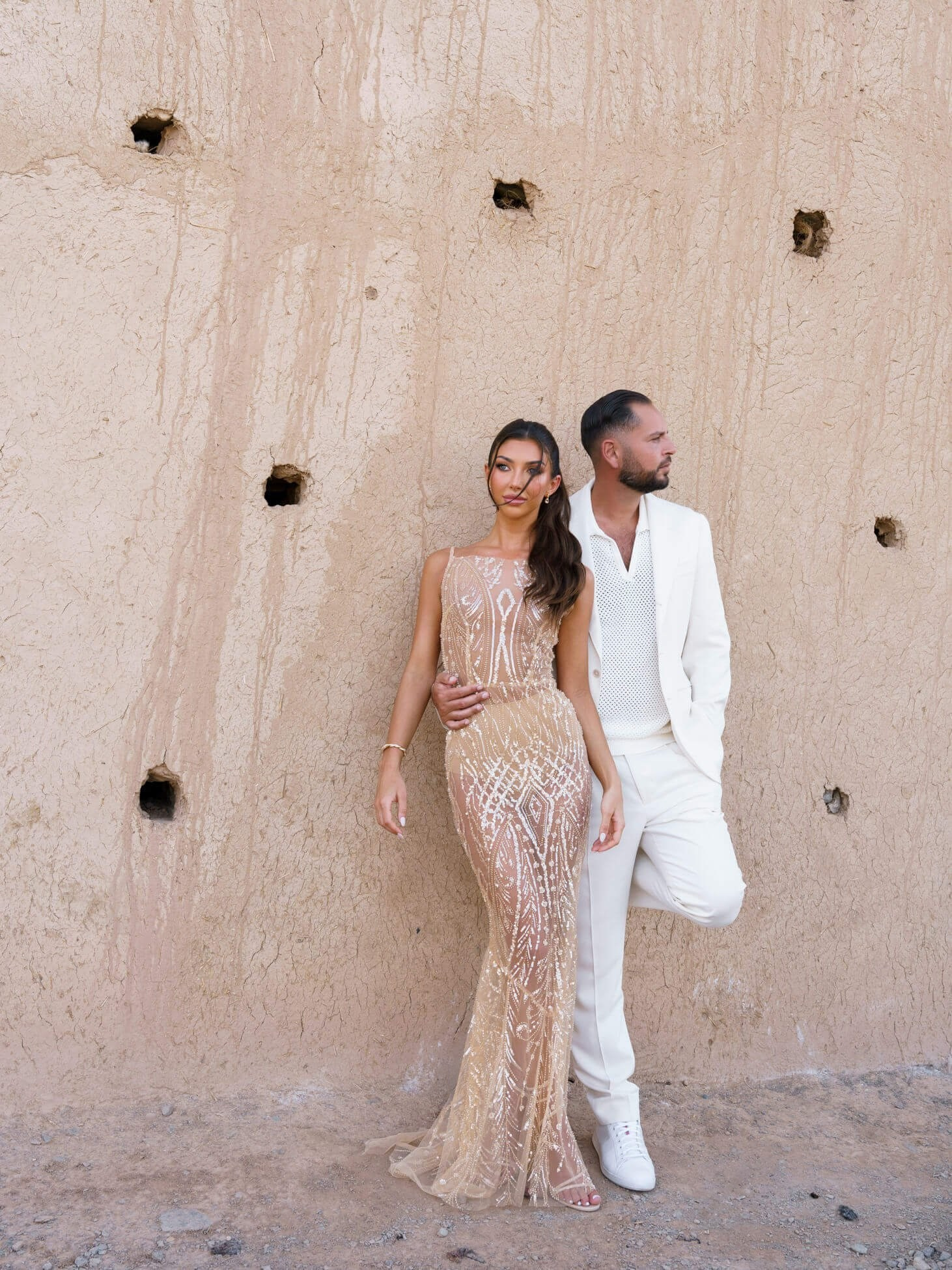 Couple standing against textured wall during luxury desert wedding portraits, Morocco
