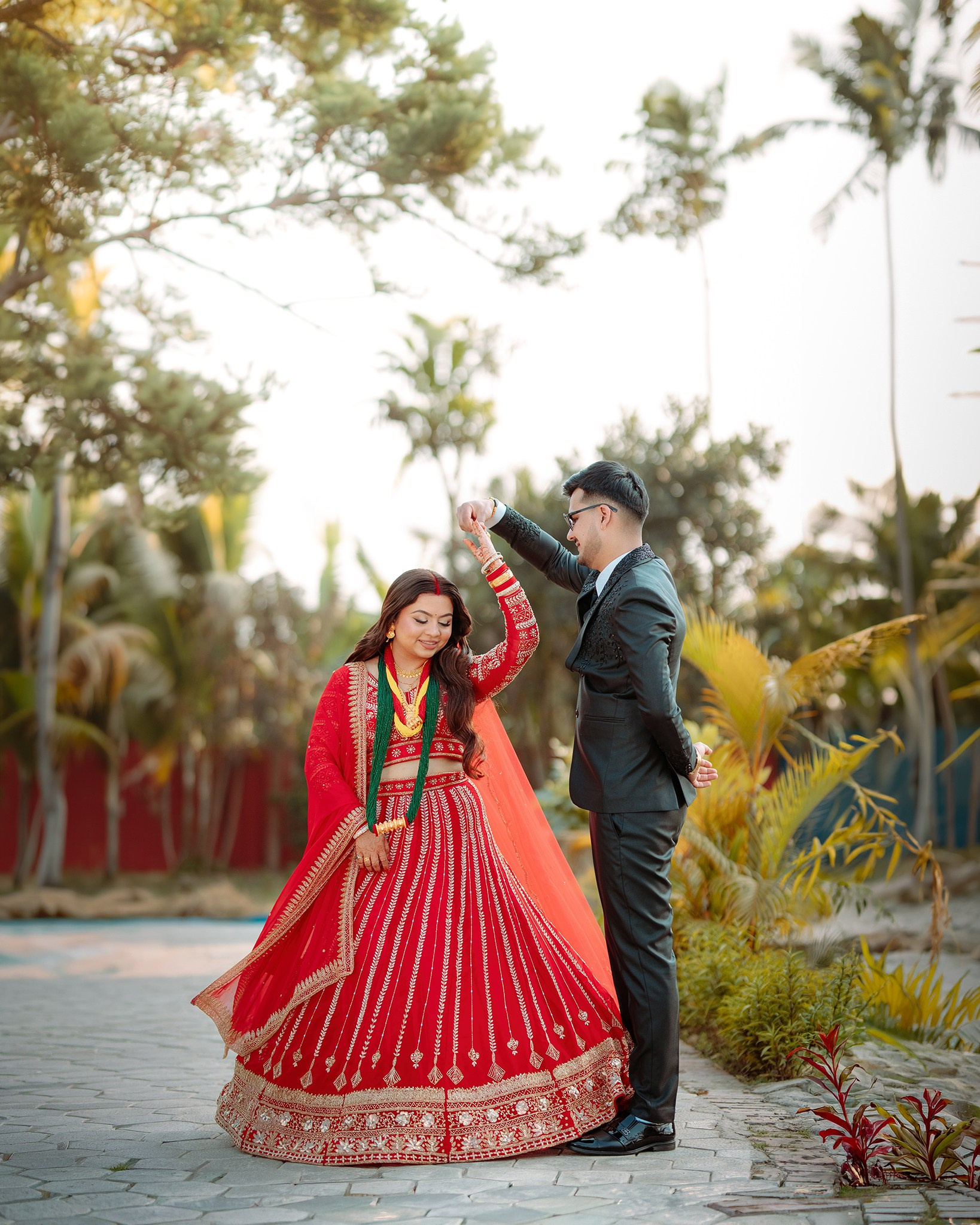 Romantic outdoor portrait of a Nepali couple with the groom twirling the bride wearing a beautiful red bridal lehenga and green pote. Professional outdoor pre-wedding photography by Poudel Digital Photography in Butwal Nepal.