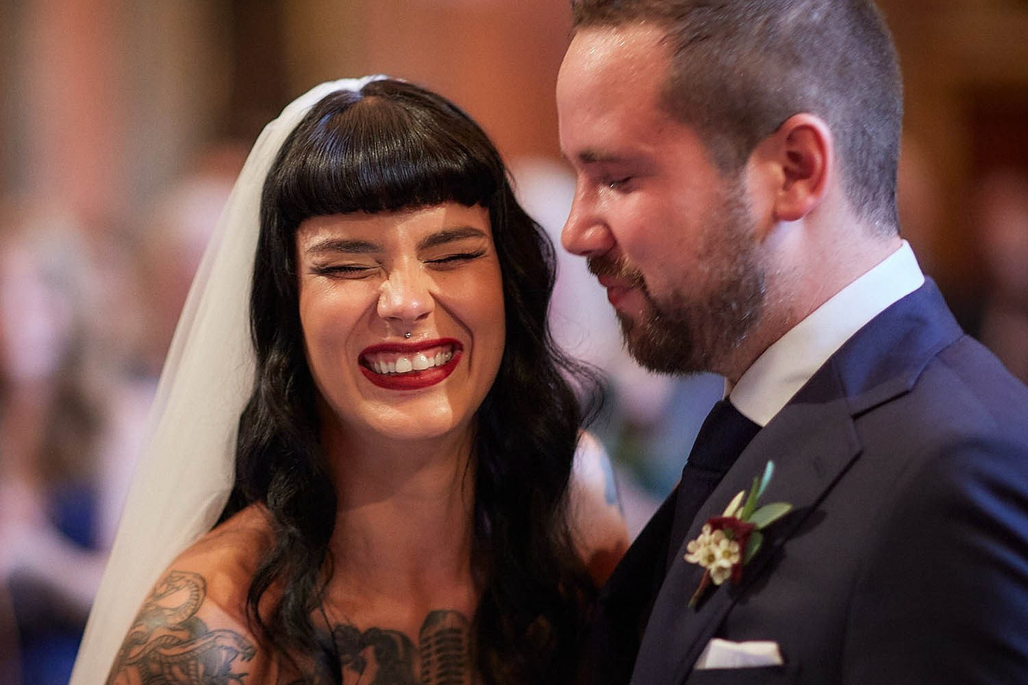 Bride beaming at teary-eyed groom during an intimate ceremony moment.