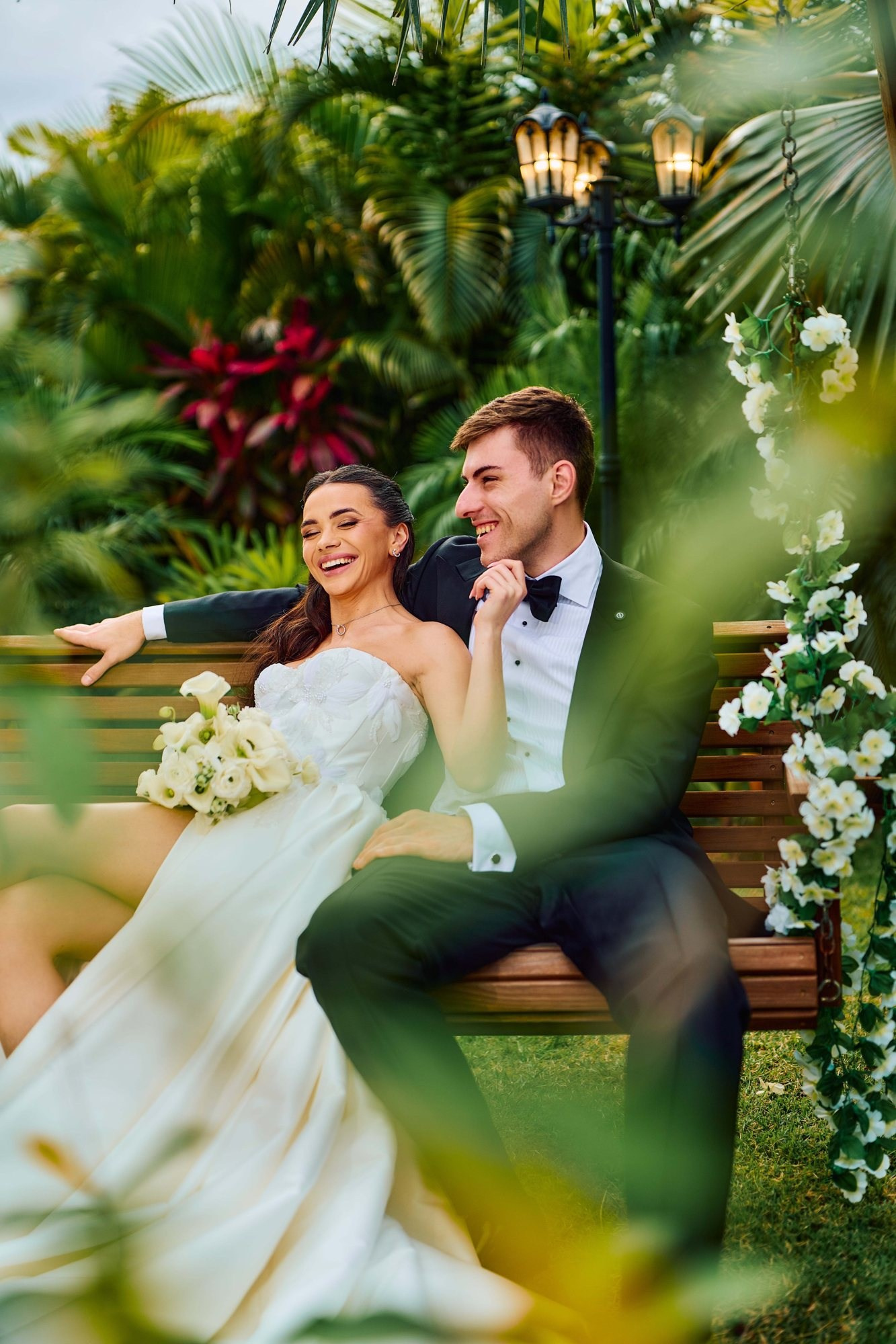 Tropical wedding photography Miami — newlyweds laughing on a garden swing under palms