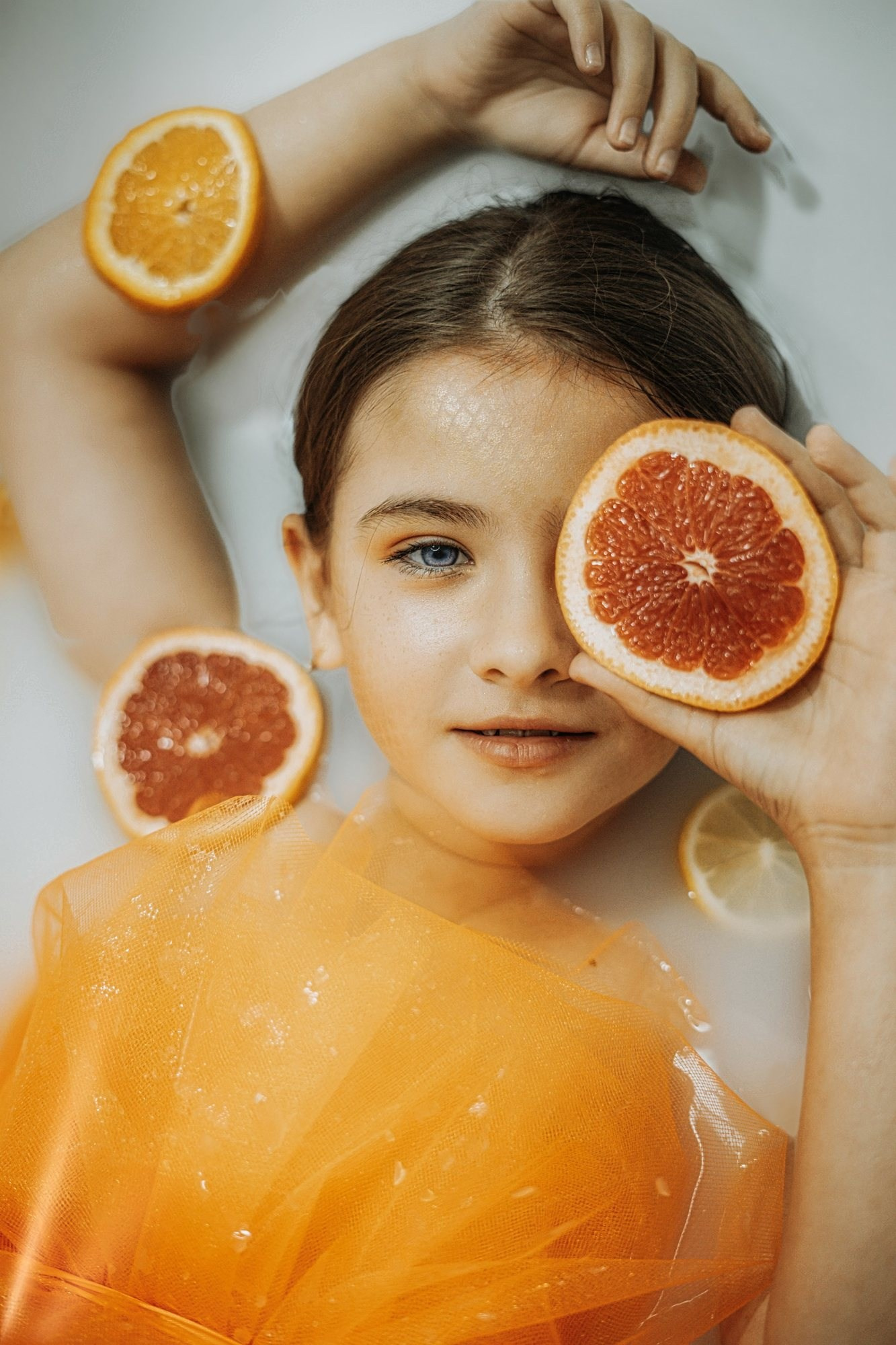 Creative kids portrait Miami — girl with citrus slices in a milk bath