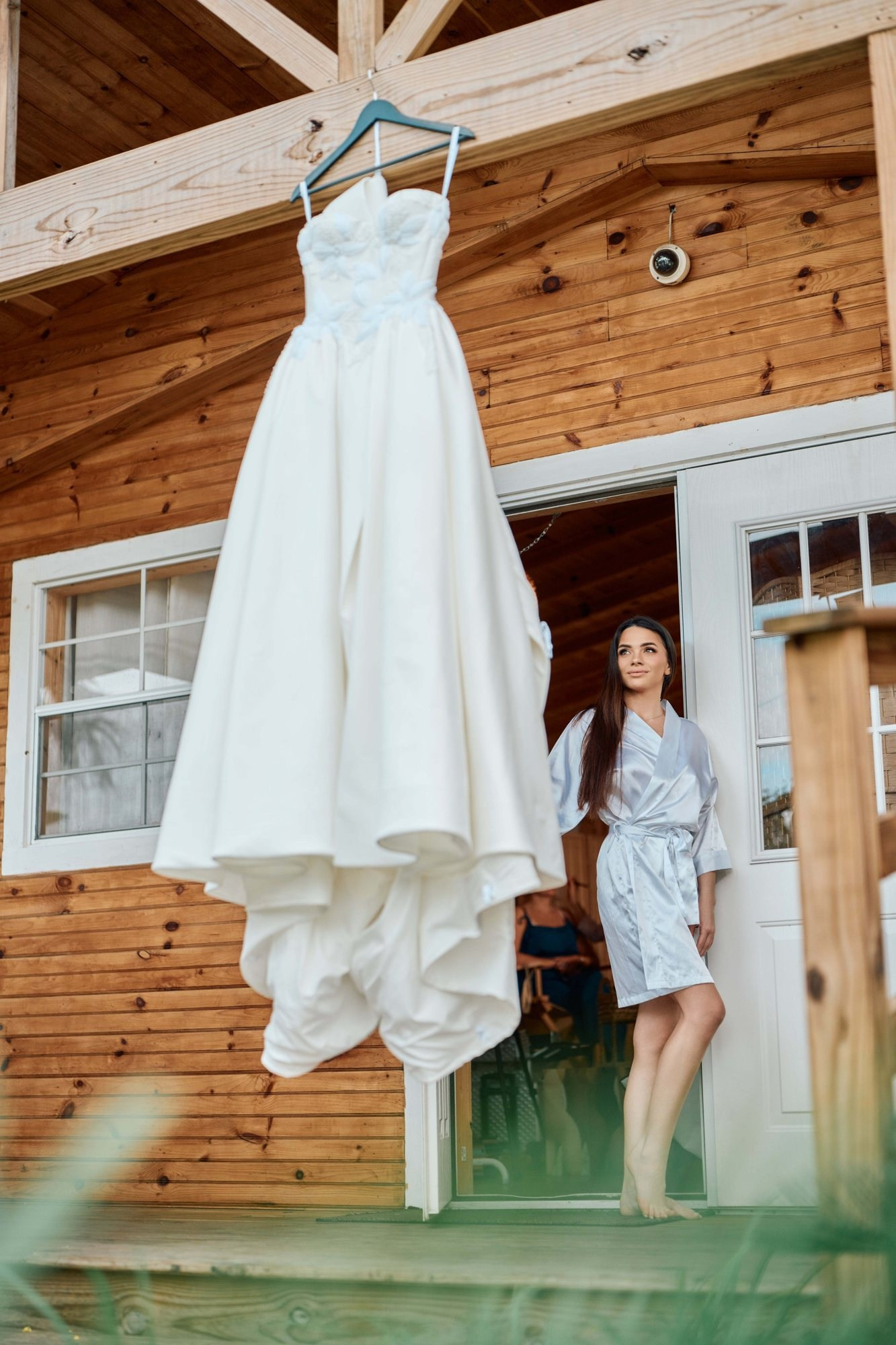 Wedding dress photos Miami — gown hanging on a wooden cabin with bride in robe