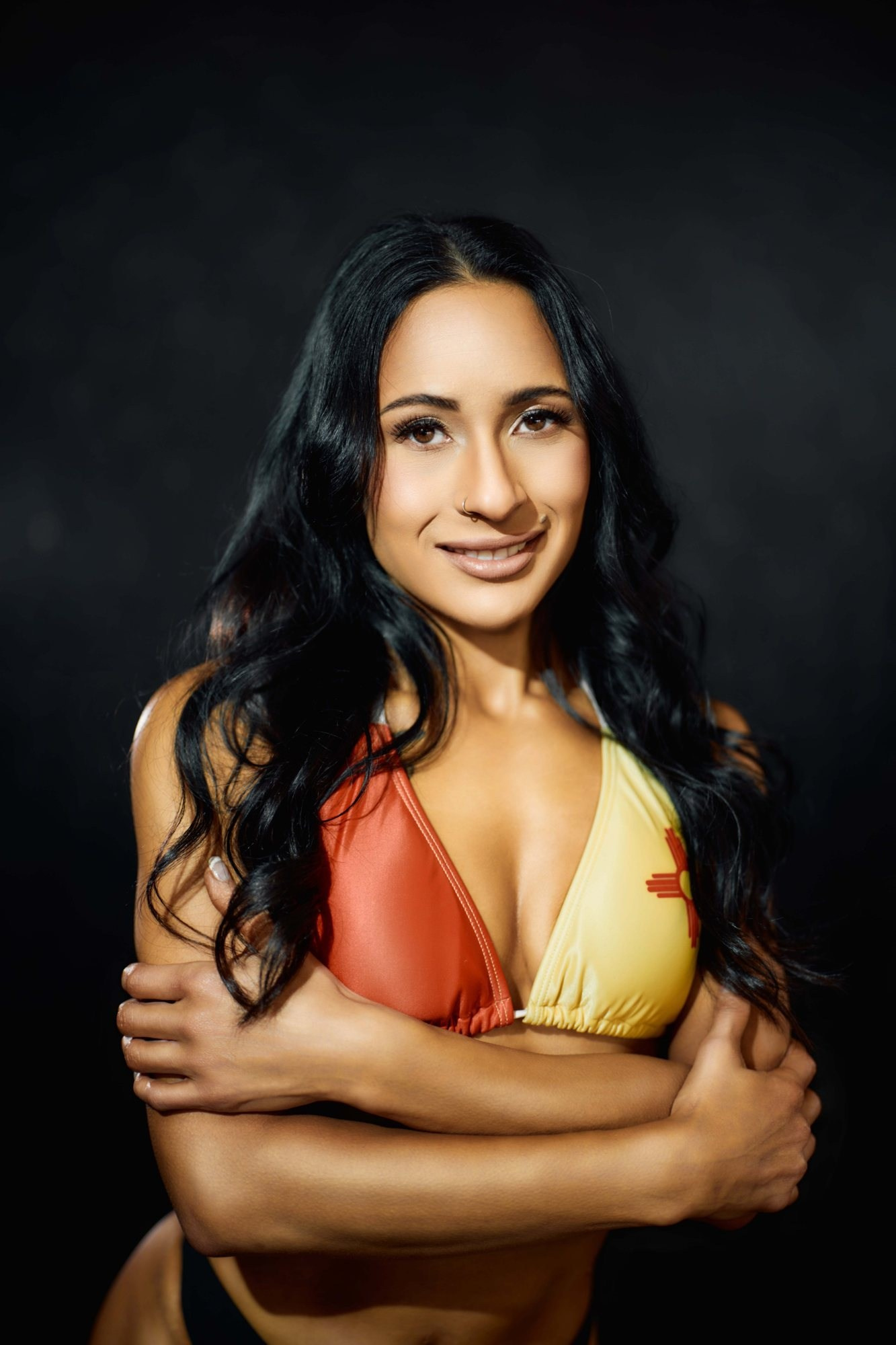 Beauty headshot Miami — woman with long dark hair in a colorful swimsuit, dark studio