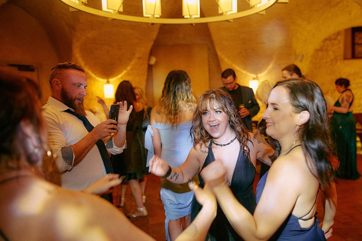 Group of guests dancing singing together at energetic wedding party.