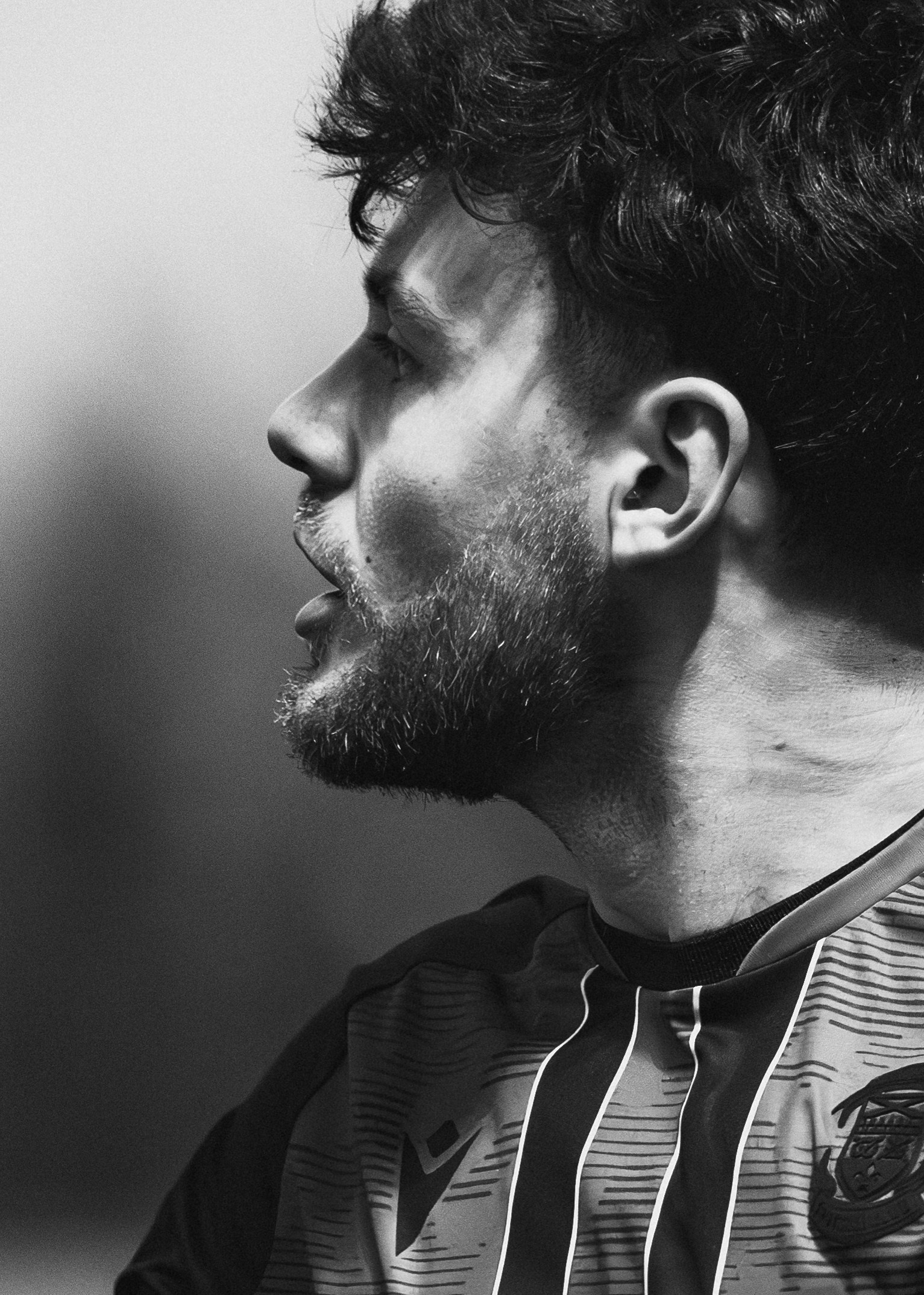 Black and white football portrait of a player in profile under dramatic lighting, cinematic sports photography.