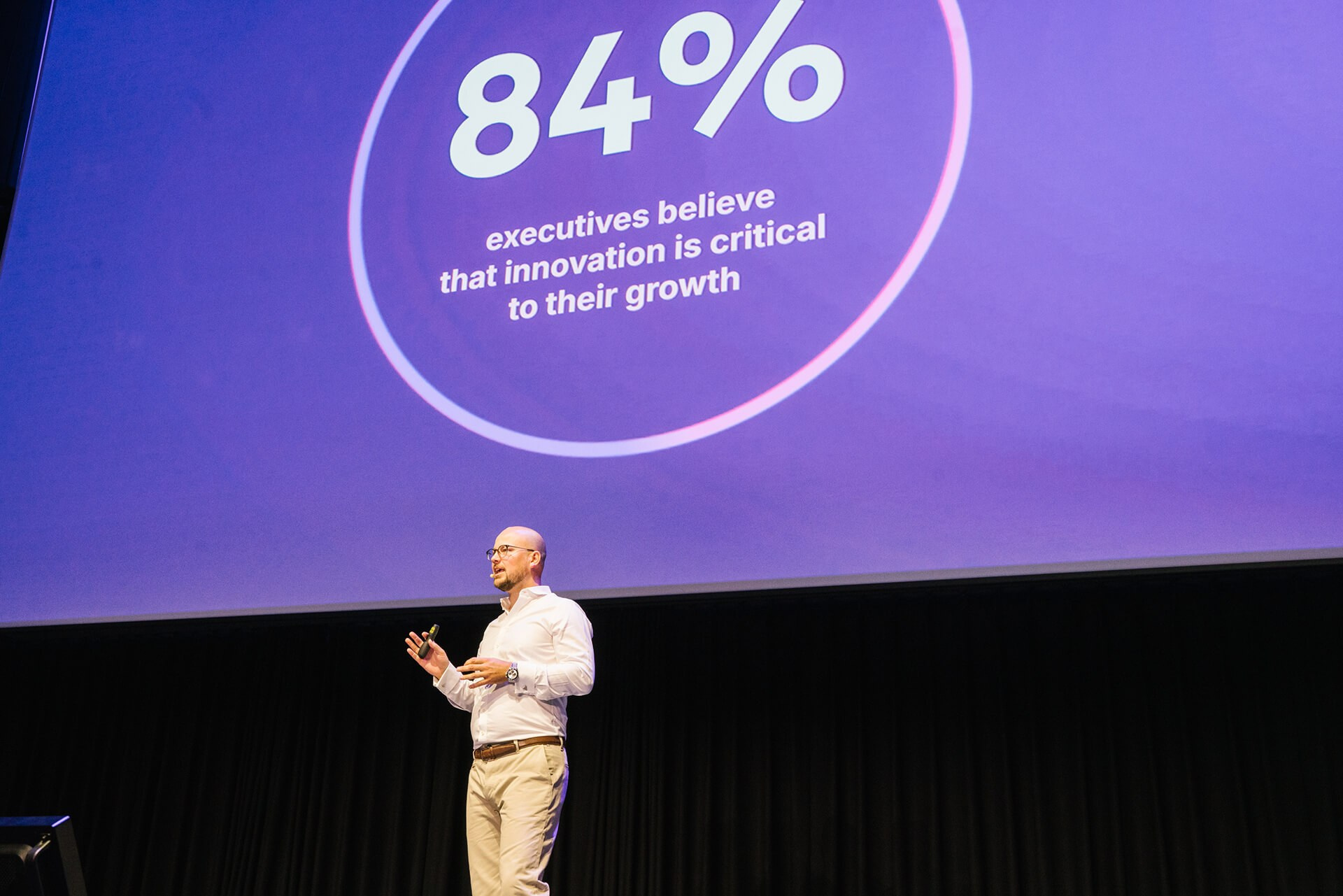 Keynote-Speaker präsentiert Daten auf großer Leinwand bei einem Business-Gipfel