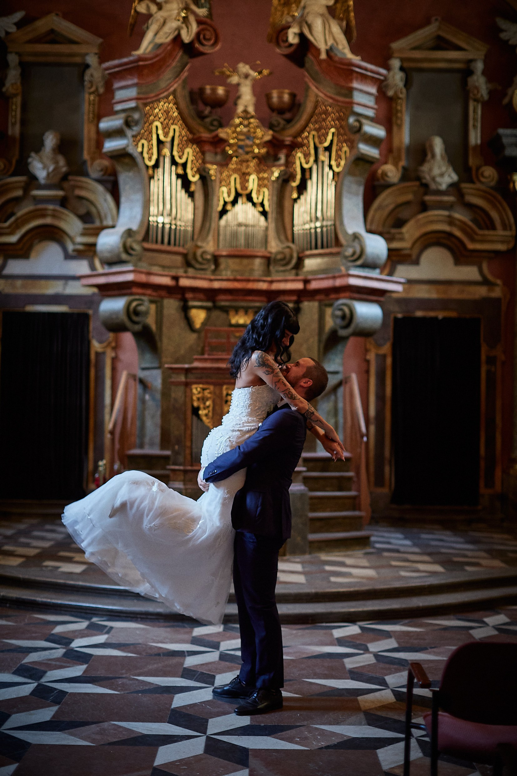 Groom lifting bride in triumphant twirl inside Mirror Chapel.