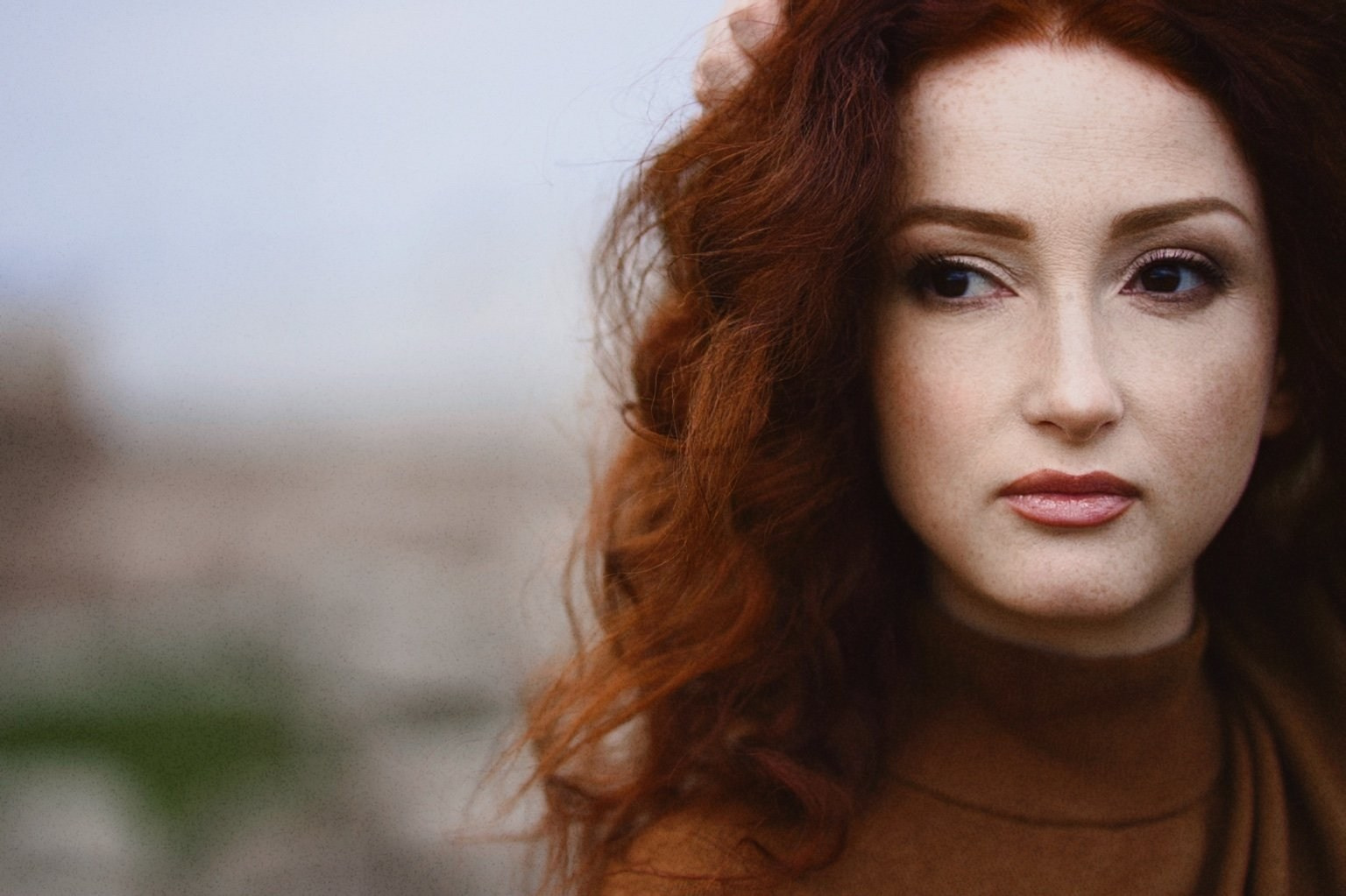 Портрет девушки с рыжими волосами на фоне города