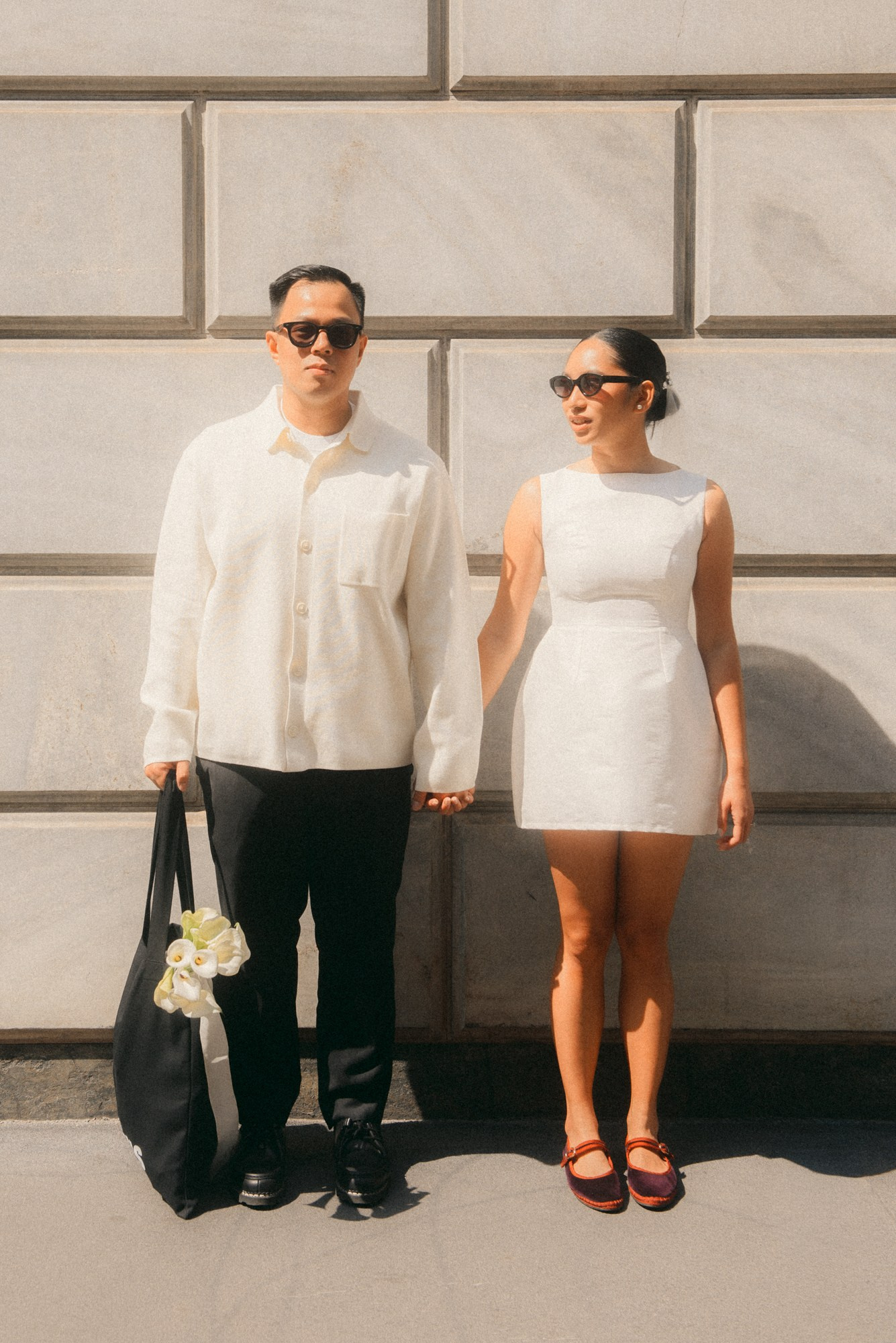 Elegant couple standing in the sunlight. A modern and stylish couple stands hand in hand in the city center, beautifully lit by soft sunlight. Their minimalist white outfits and urban setting create a refined editorial-style portrait, ideal for civil wedding or engagement photography. urban couple, civil wedding, minimalist style, white outfits, natural light, editorial photography, Milan photoshoot, love story, modern couple, anastasiia buchinskaia photographer, anamilanofoto