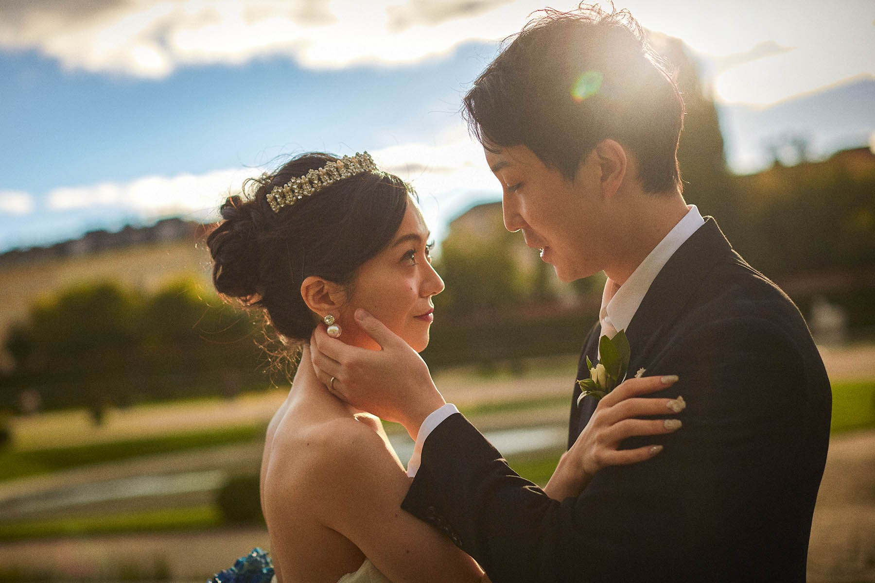 Groom caressing bride's face with sun flare Belvedere Palace.