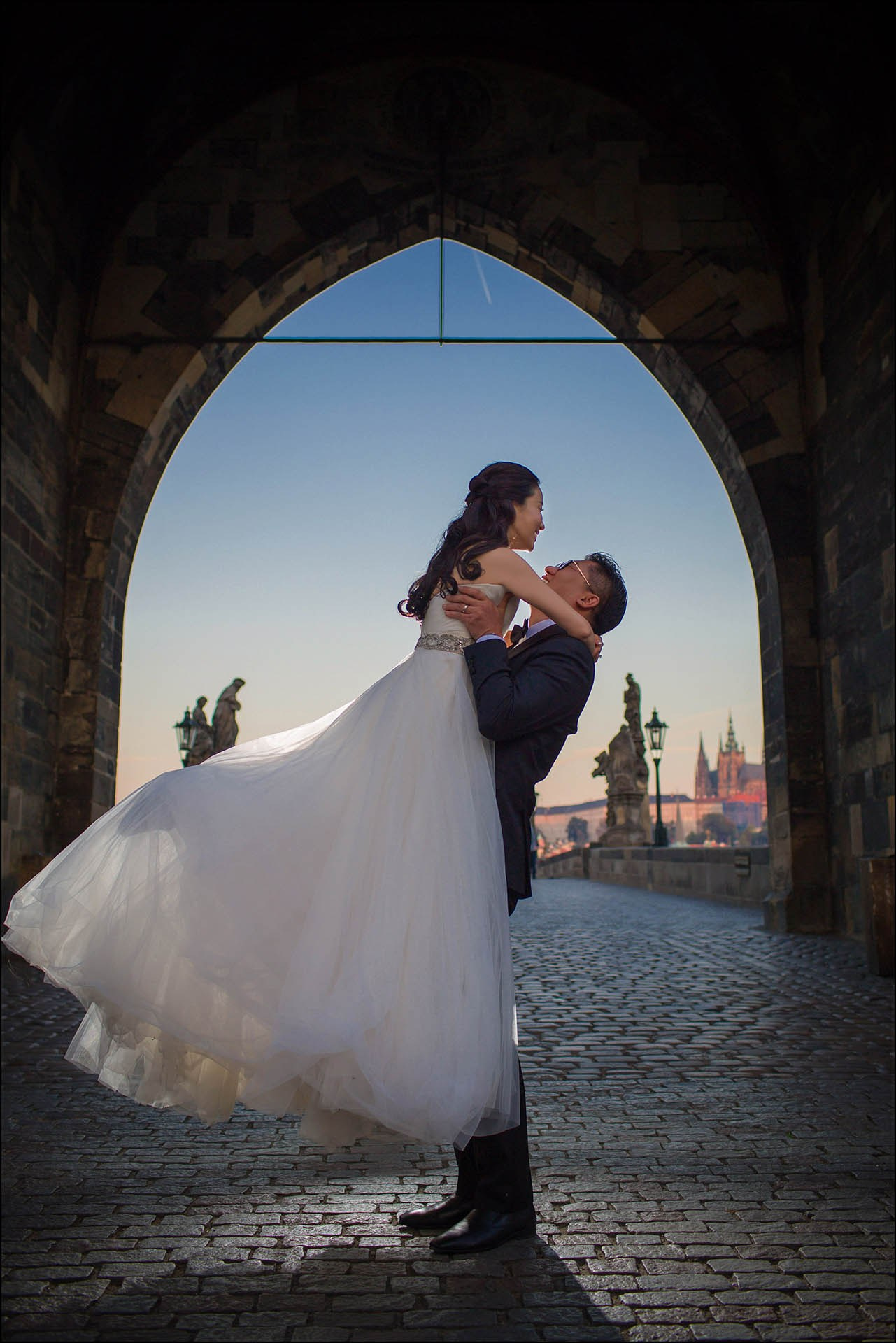 Cedric Son twirls Catherine gothic arch Charles Bridge Prague wedding portrait.