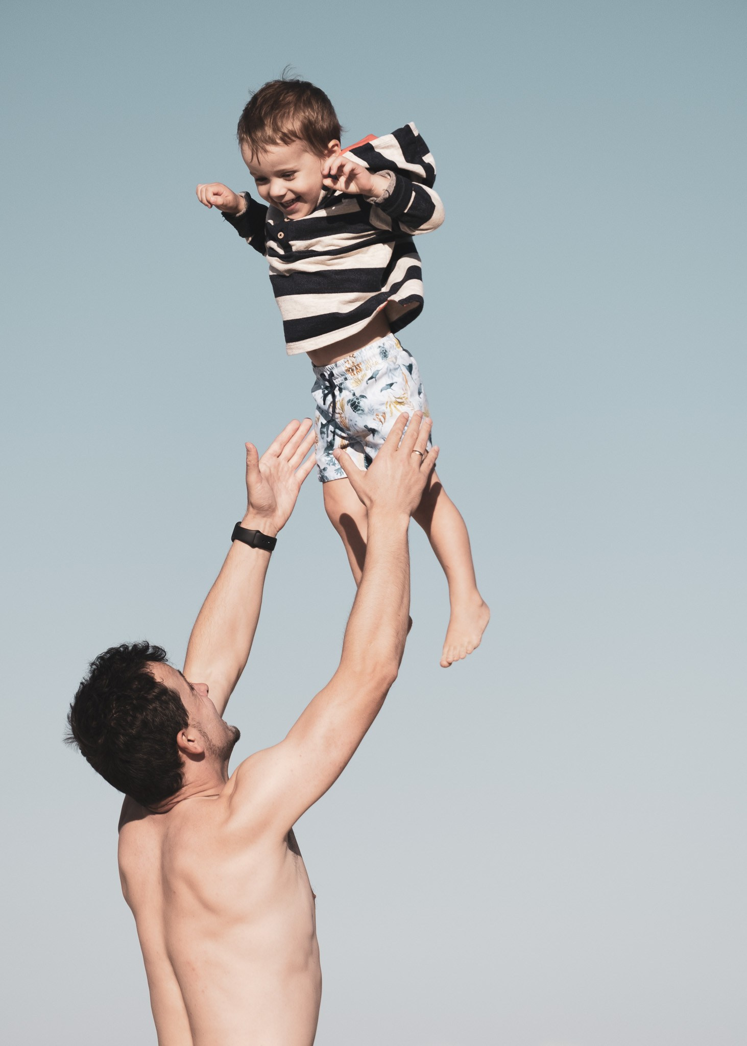 Parents playing with their child by the ocean, natural family beach photoshoot.