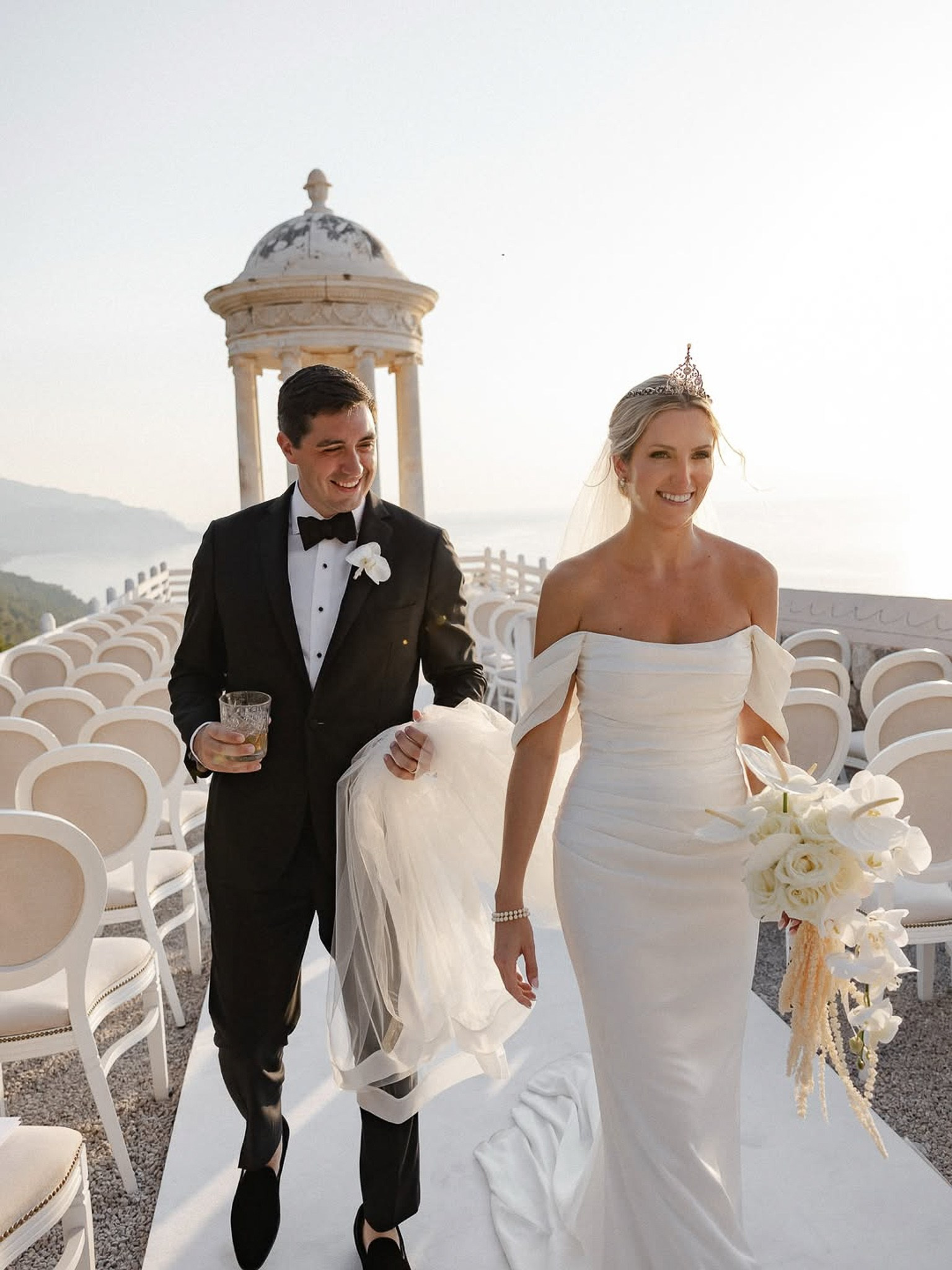 Bride and groom walking down the aisle together, groom holding a drink, after their Son Marroig wedding