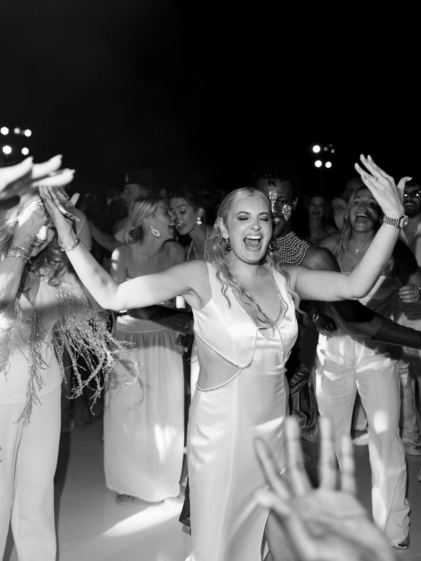 Black and white photo of guests dancing during luxury desert wedding reception