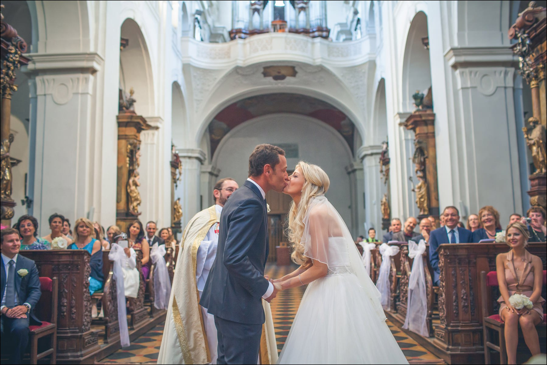 Newlyweds sharing joyful first kiss at St. Thomas Church Prague