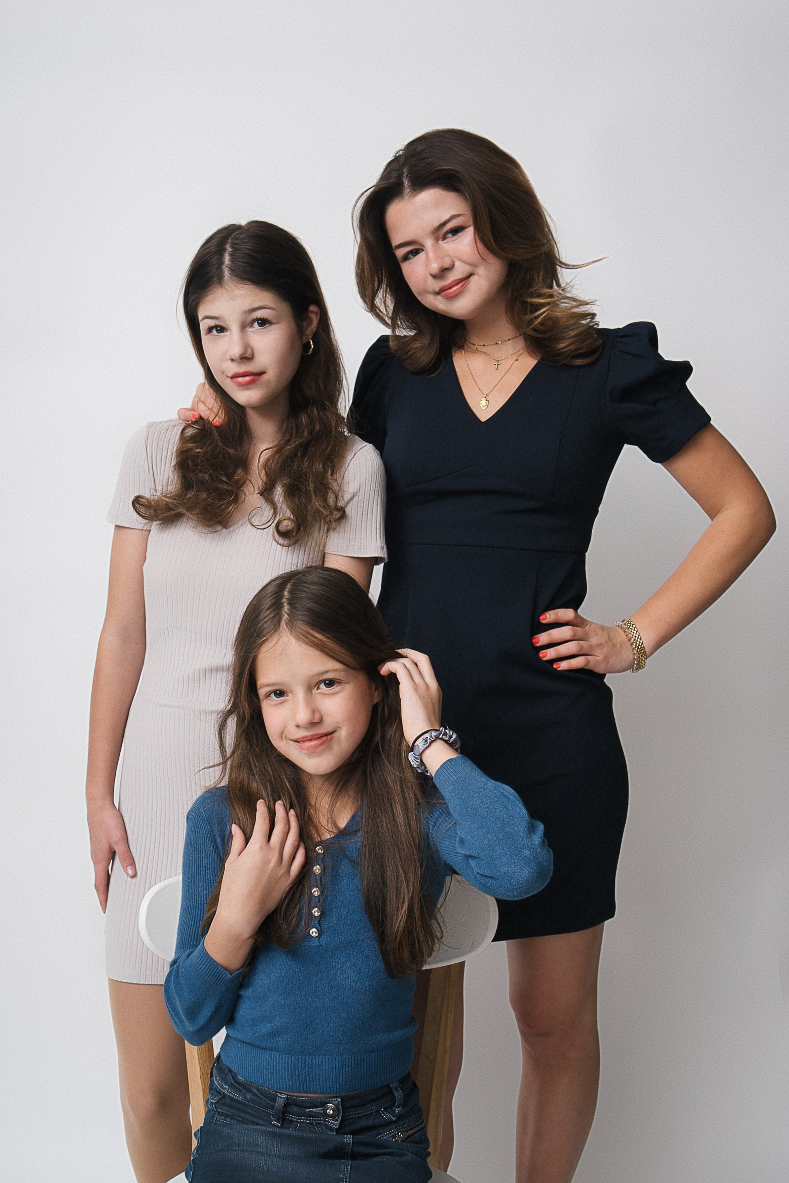Family portraits of three sisters are close together, smiling and hugging