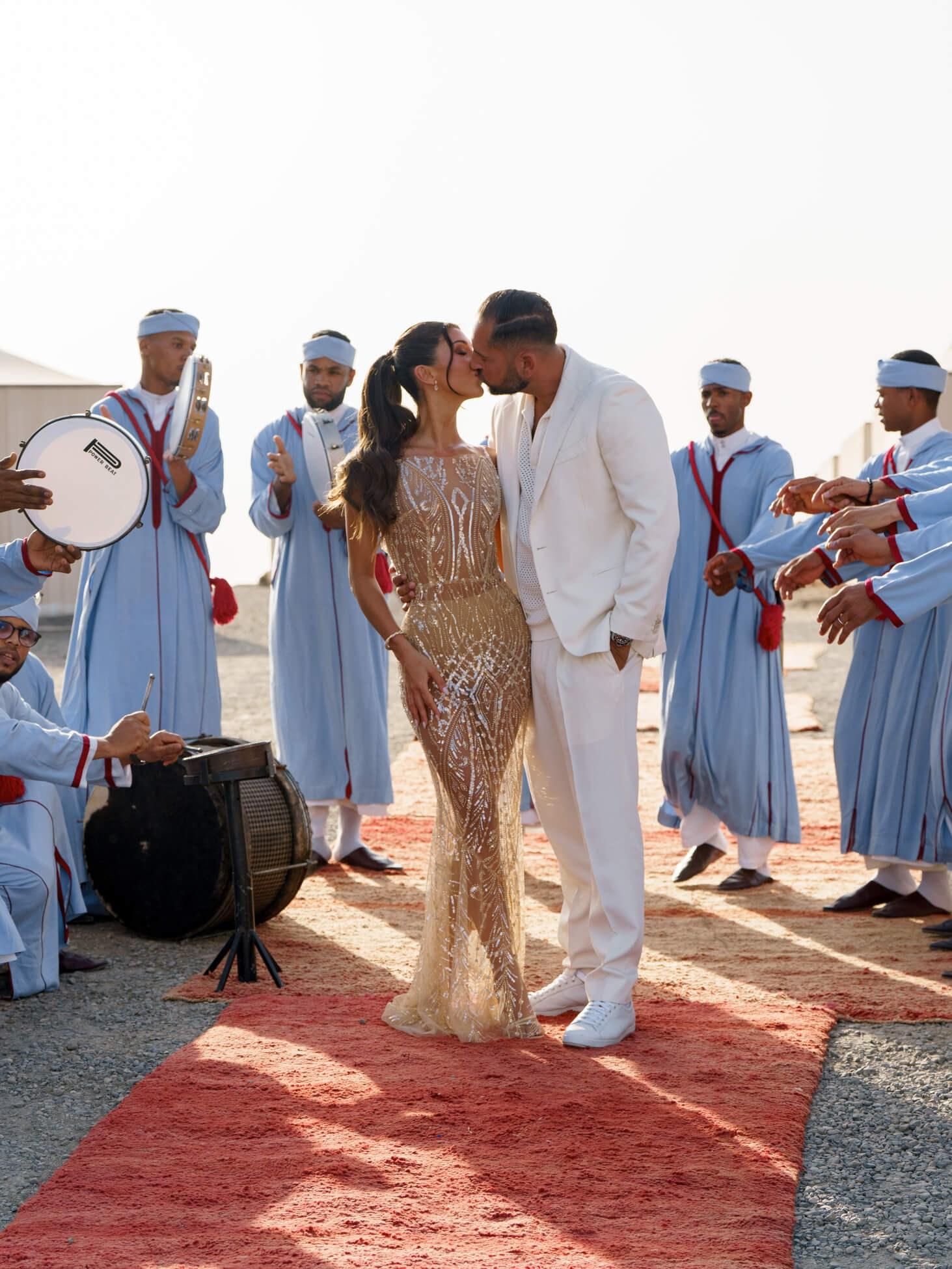 Newlyweds walking with musicians during luxury desert wedding reception, Morocco