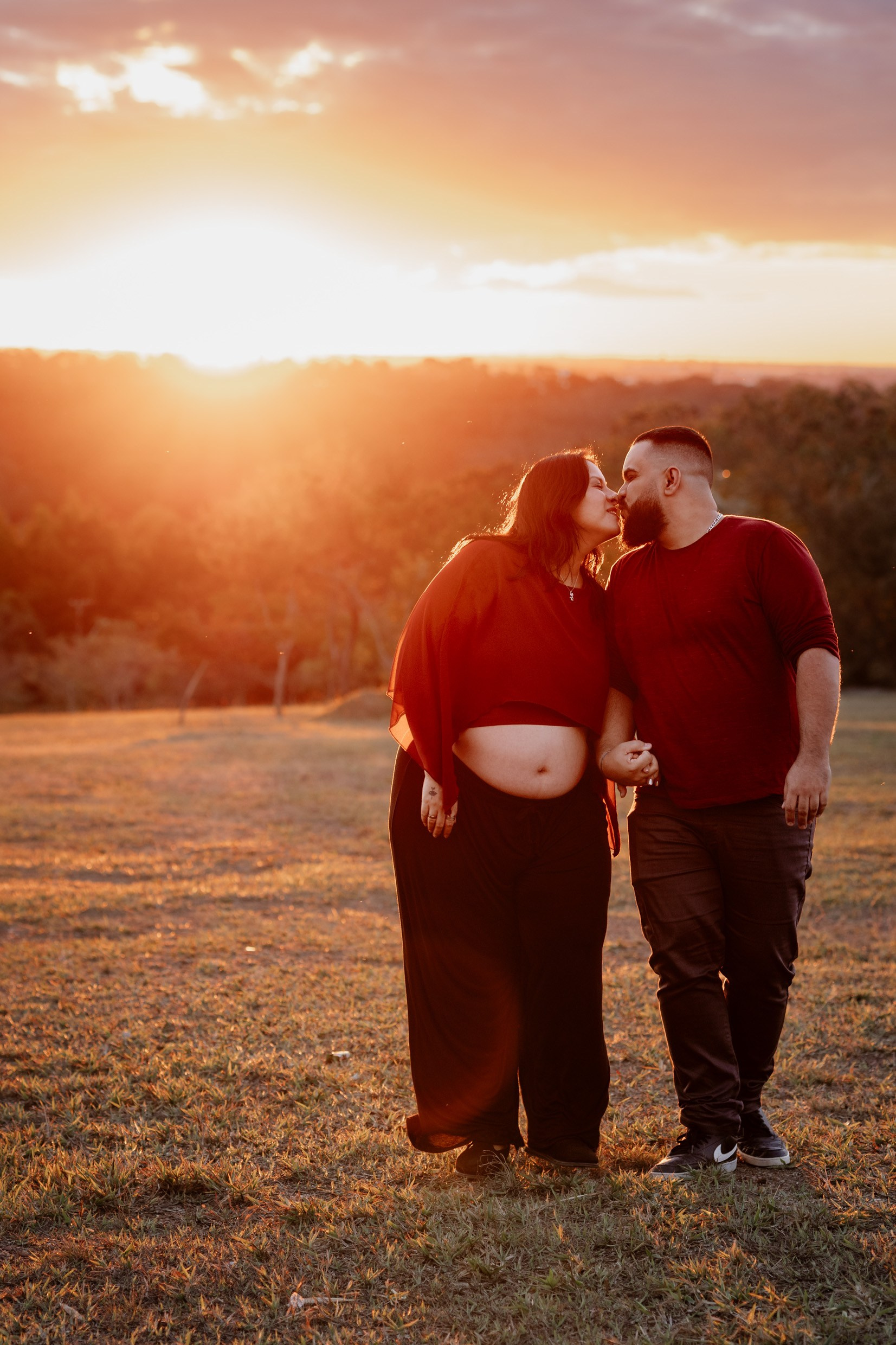 Casal se olha com carinho durante ensaio de maternidade.