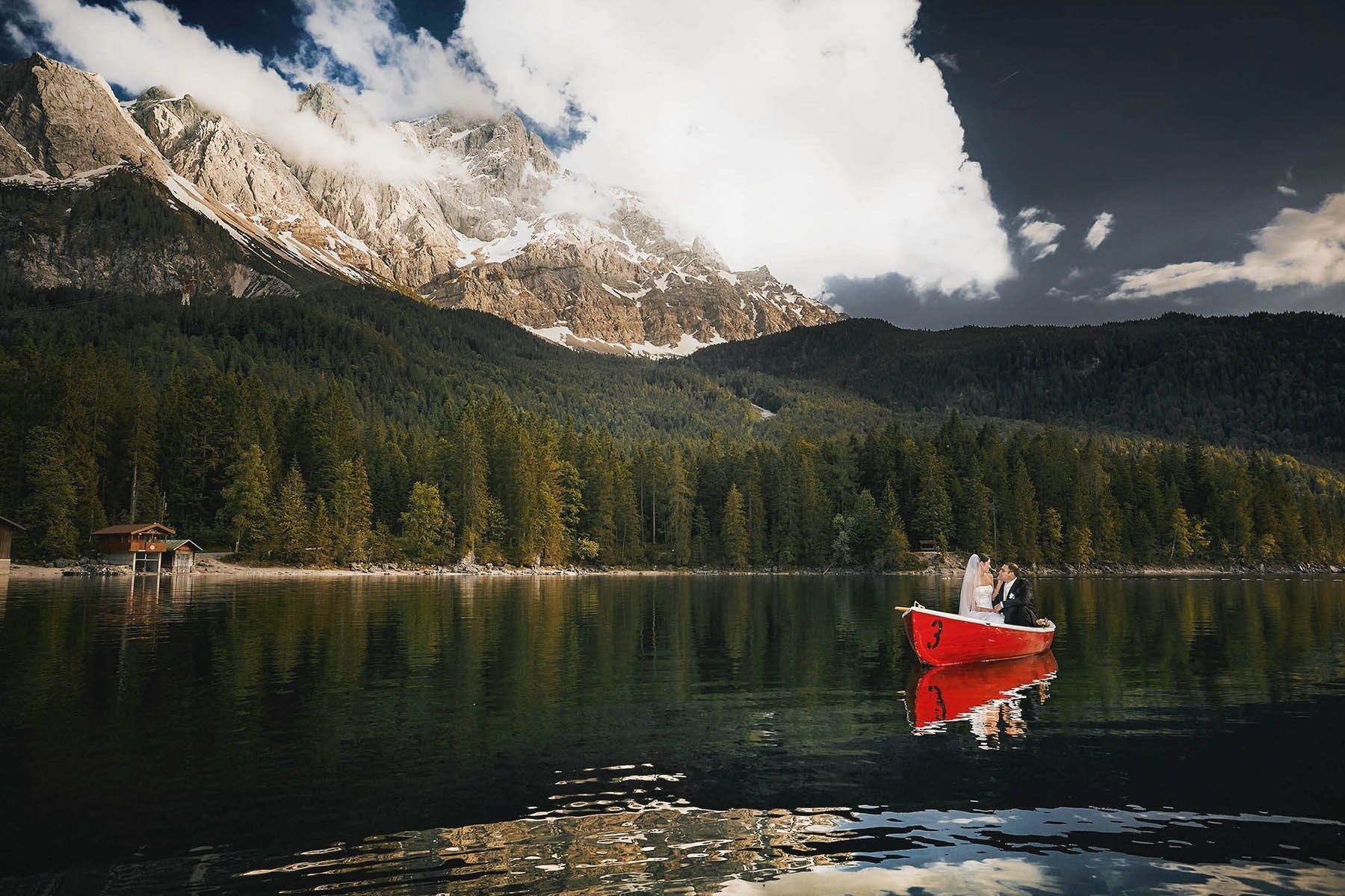 Newlyweds in a red rowboat on Lake Eibsee, a German destination wedding