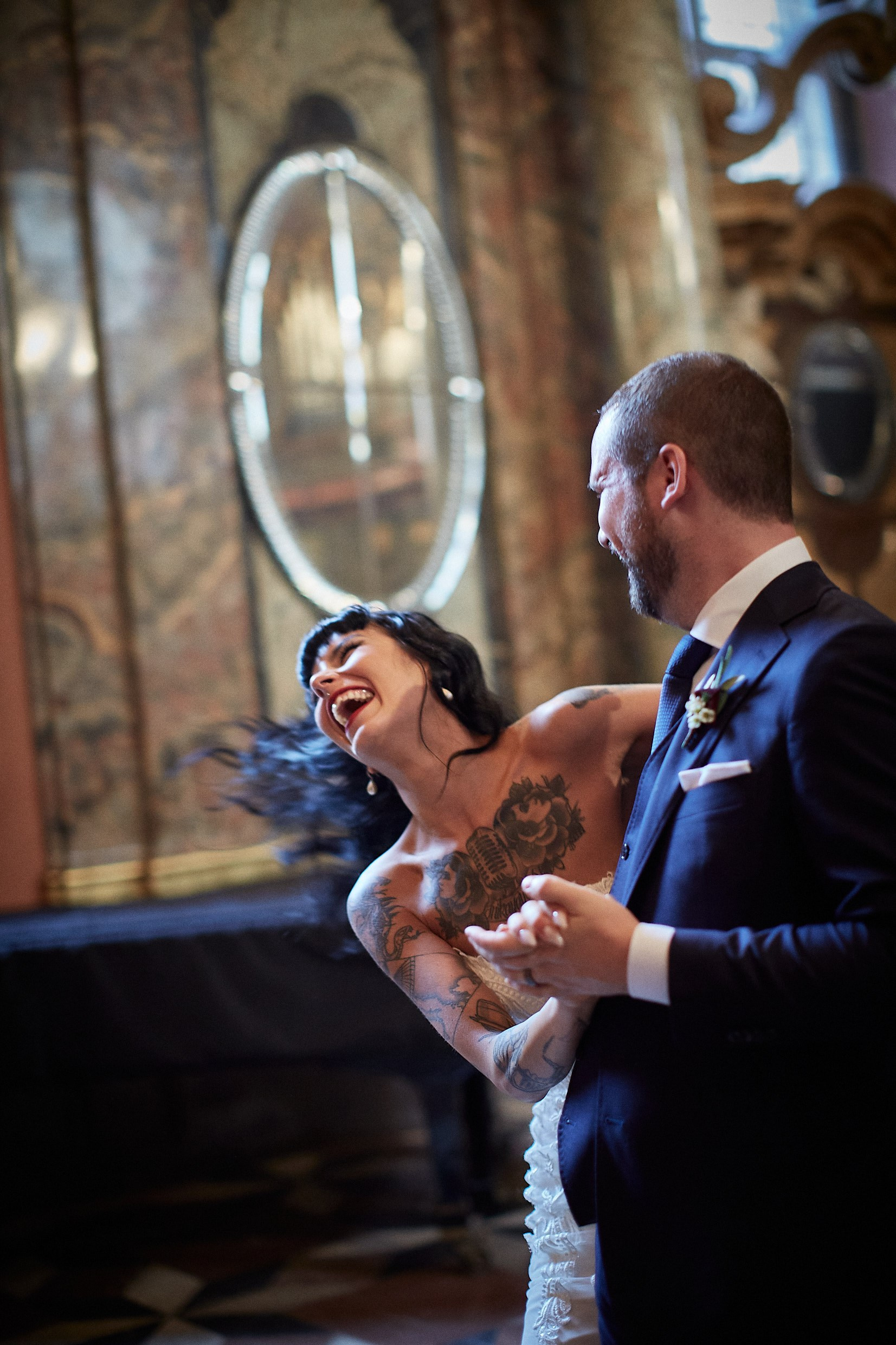Bride laughing ecstatically during joyful spin with groom.
