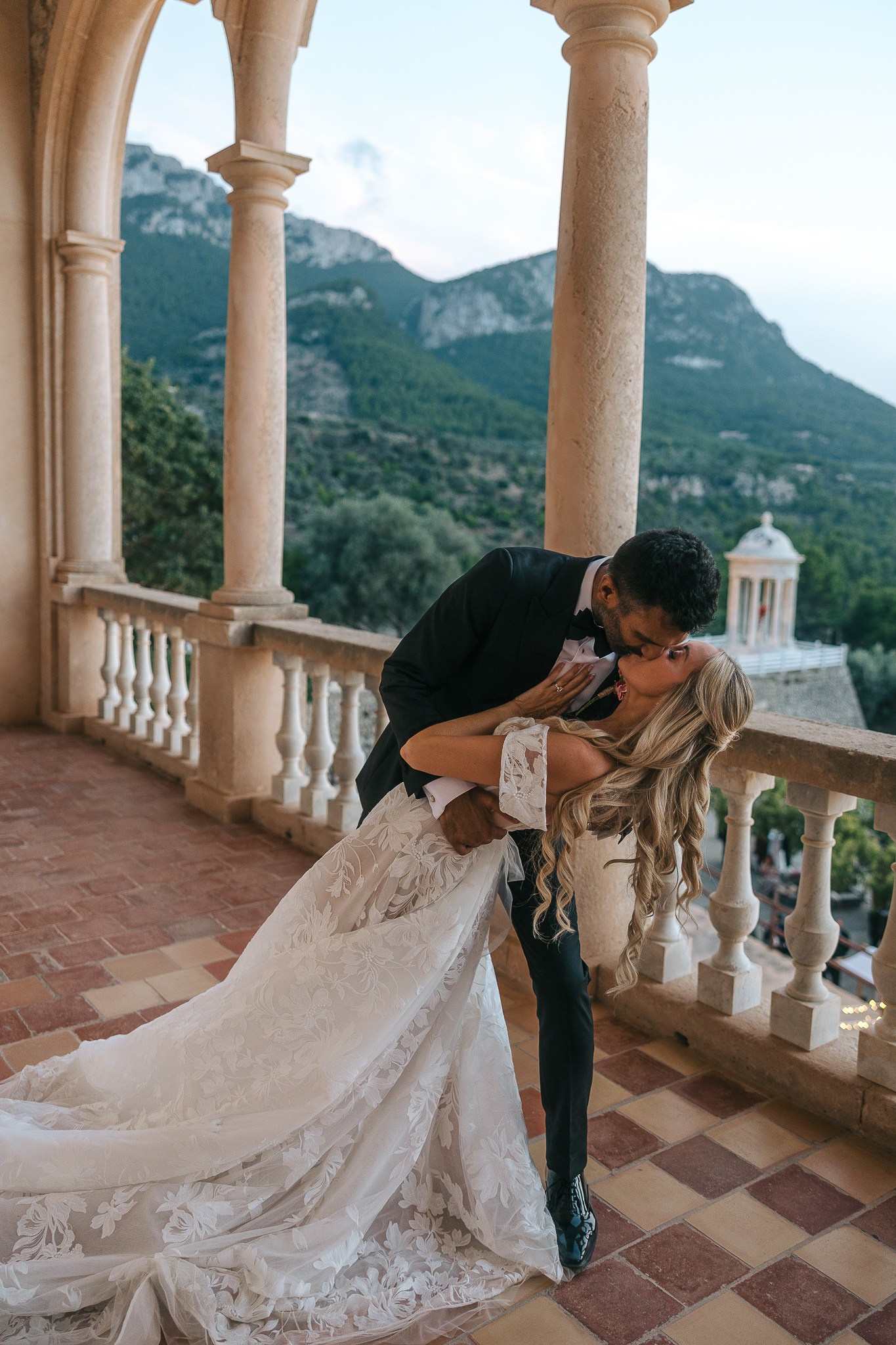 Bride and groom kissing on a balcony overlooking the mountains after their Son Marroig wedding