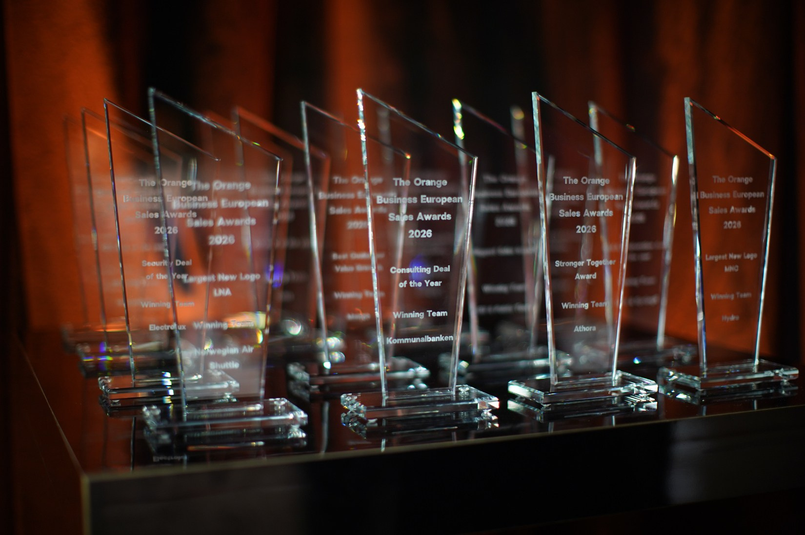 Row of crystal glass awards displayed on stage for Orange Business European Sales Kick-Off 2026 adventure-themed gala dinner at Hilton Prague.