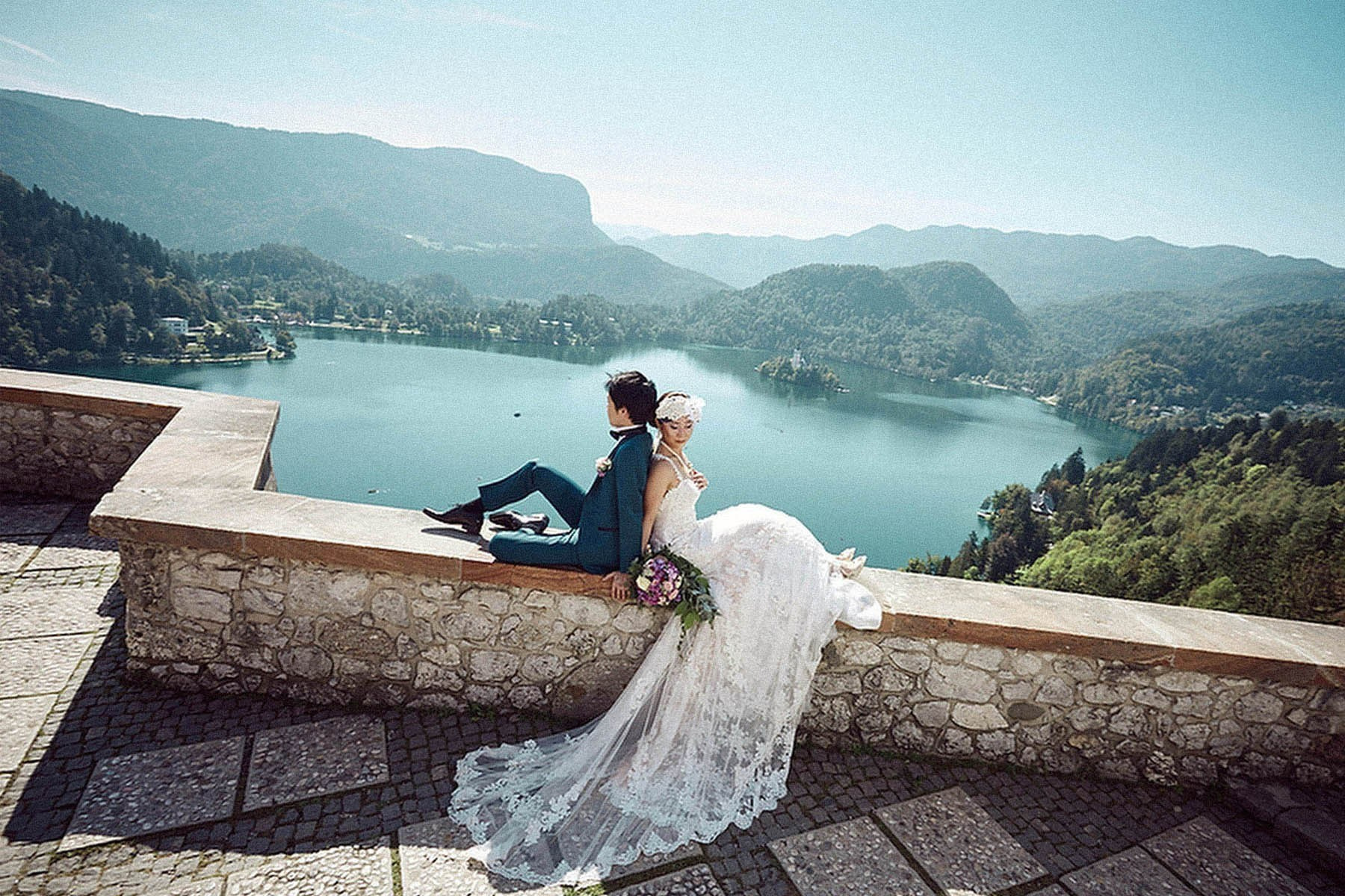 Stylish newlyweds on Bled Castle wall overlooking Lake Bled, Slovenia wedding