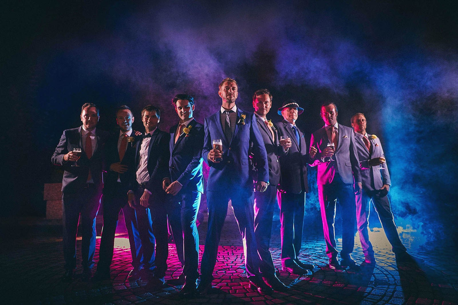 Groom and best men posing with smoke grenades at night.