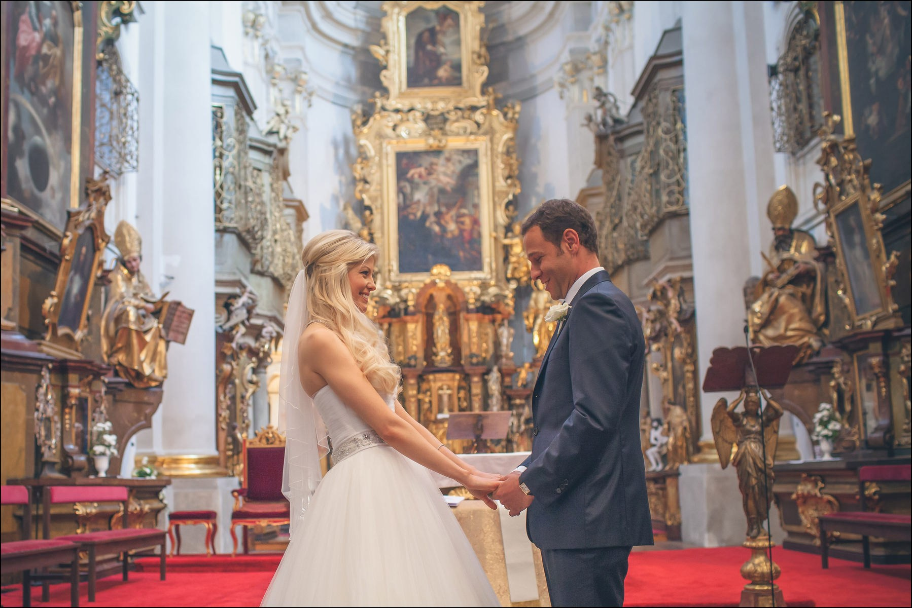 Bride taking groom's hand for ring exchange at Baroque church Prague