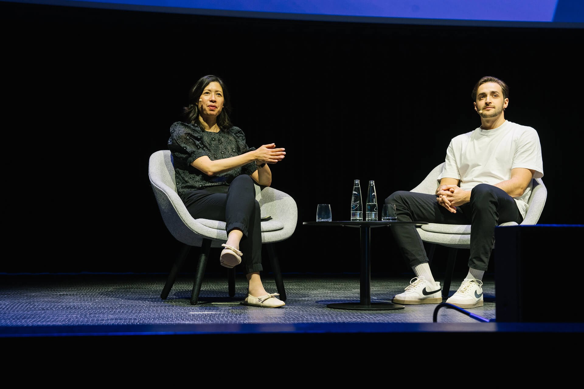 Two speakers seated on stage during a Berlin business conference discussion