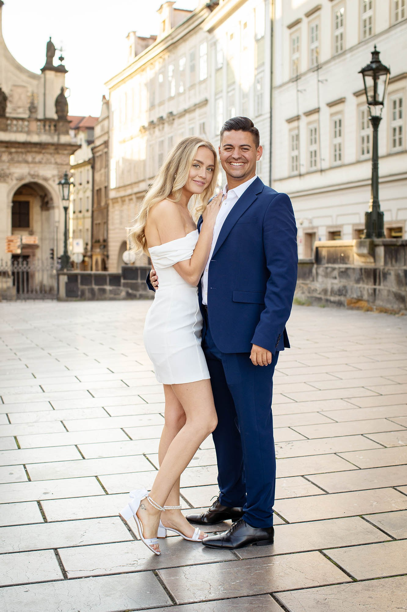 Smiling engaged couple, looking towards the camera during their engagement in Prague shortly after sunrise