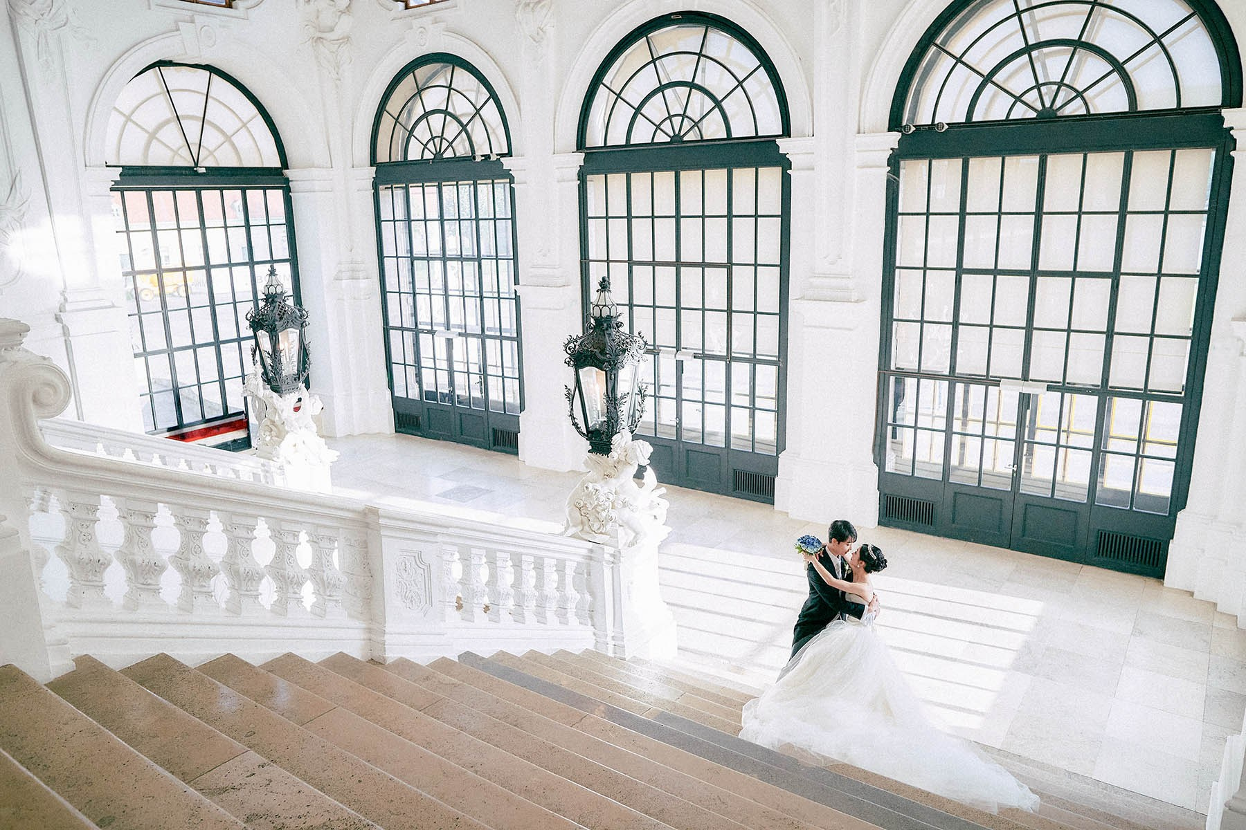 Newlyweds embracing alone at bottom of stairs Belvedere Palace.