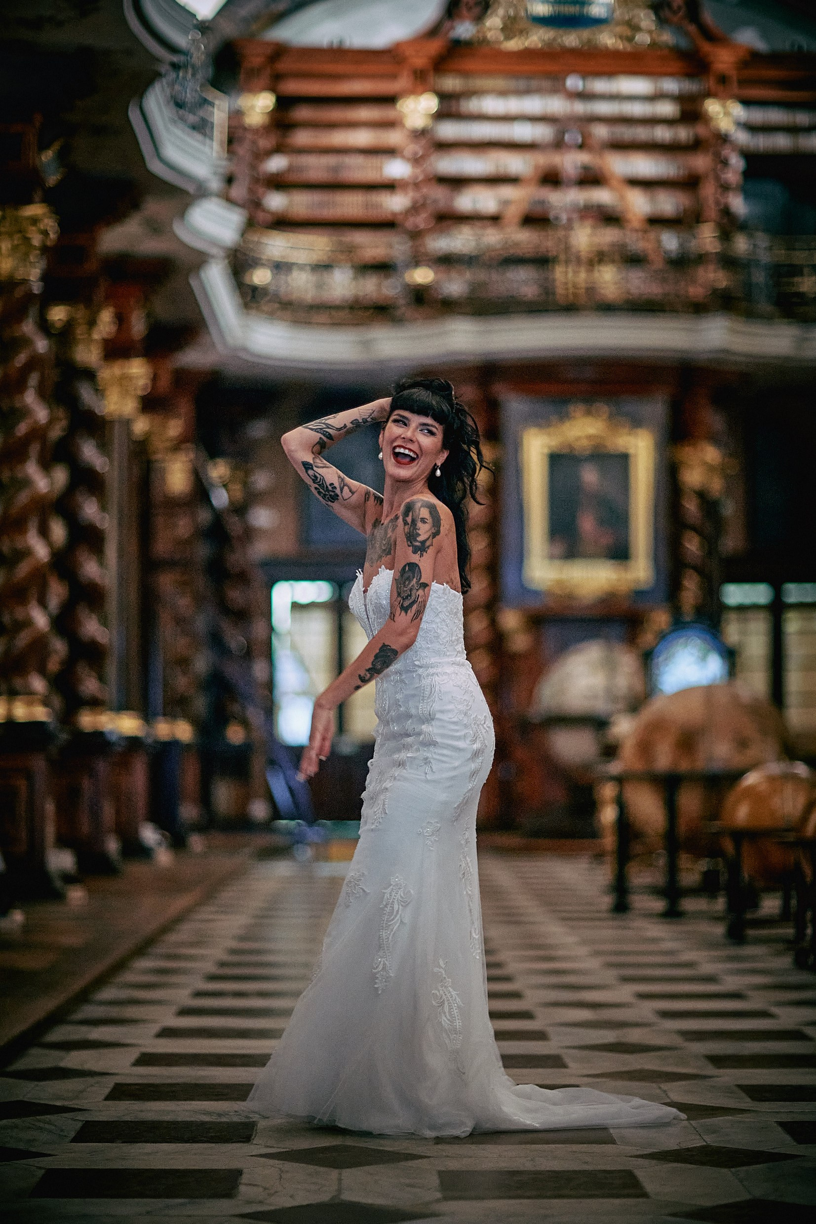 Bride laughing playfully with hair in dramatic library portrait.
