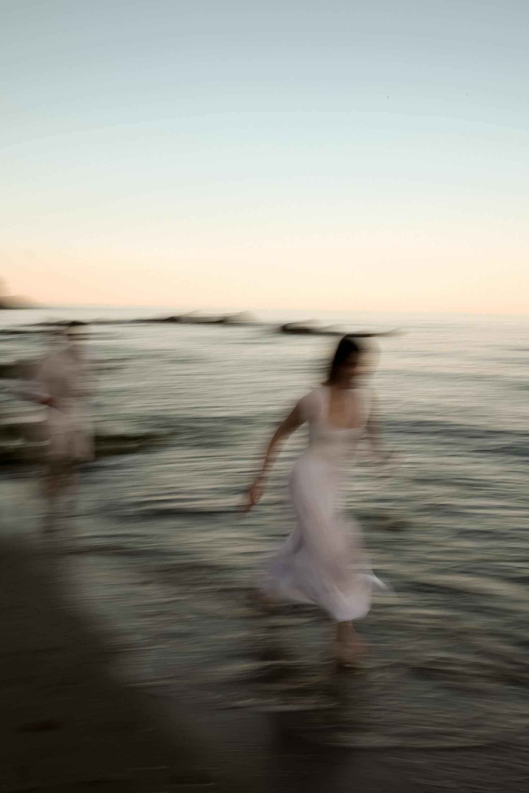 Schwarzweiß: Unscharfes Bild. Brautpaar läuft lachend durch das Meer, Braut lacht herzlich, authentische Hochzeitsfotos Costa Blanca Alicante
