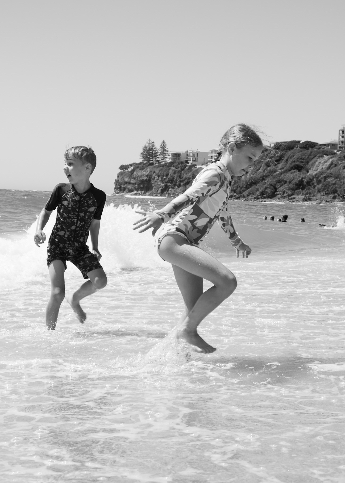 Parents playing with their child by the ocean, natural family beach photoshoot.