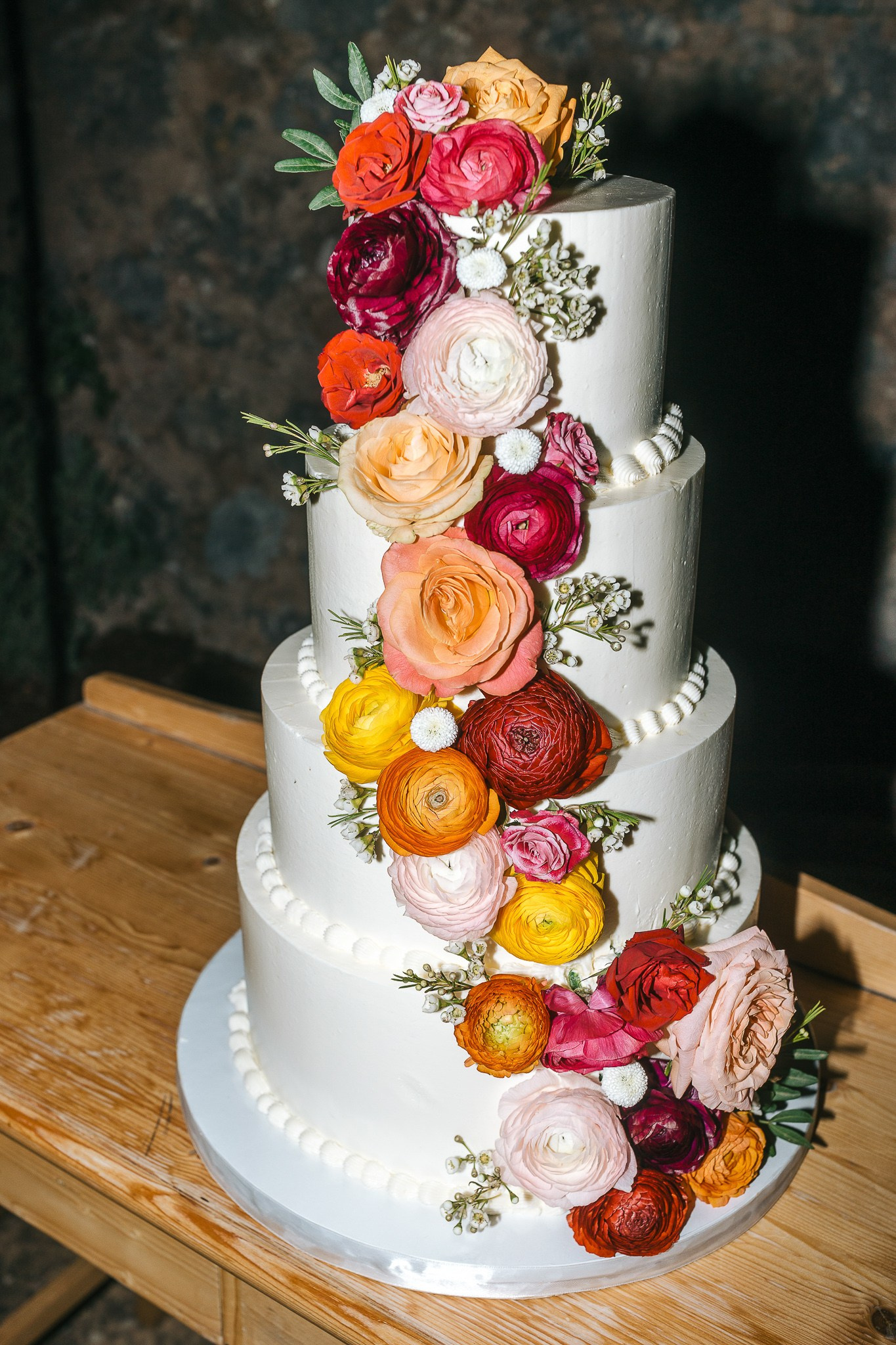 Close-up of a four-tier wedding cake decorated with colorful flowers at a Mallorca wedding