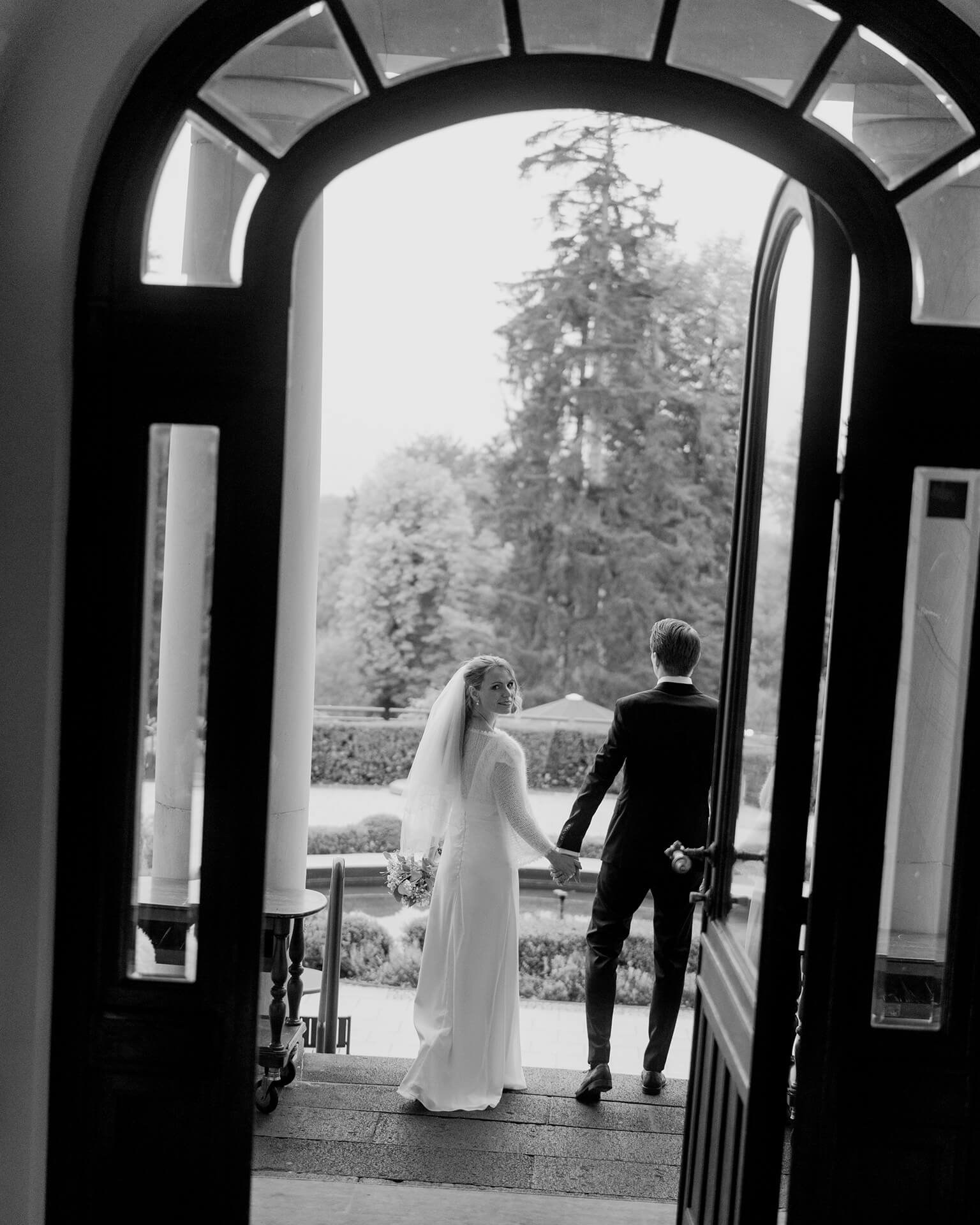 Black and white couple exiting doorway, luxury wedding at Falkenstein Grand