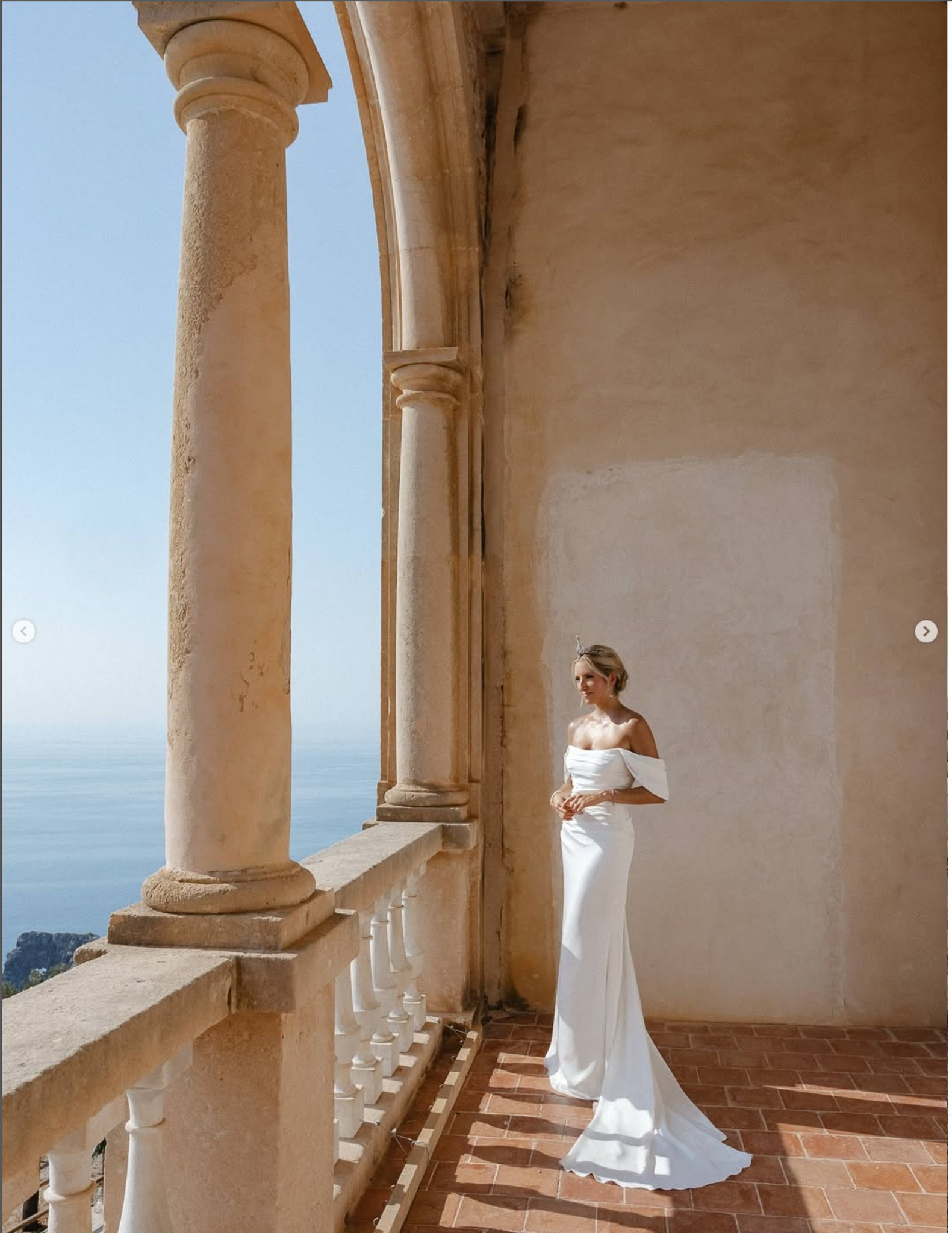 Bride in her wedding gown and tiara on a stone balcony overlooking the sea at Son Marroig