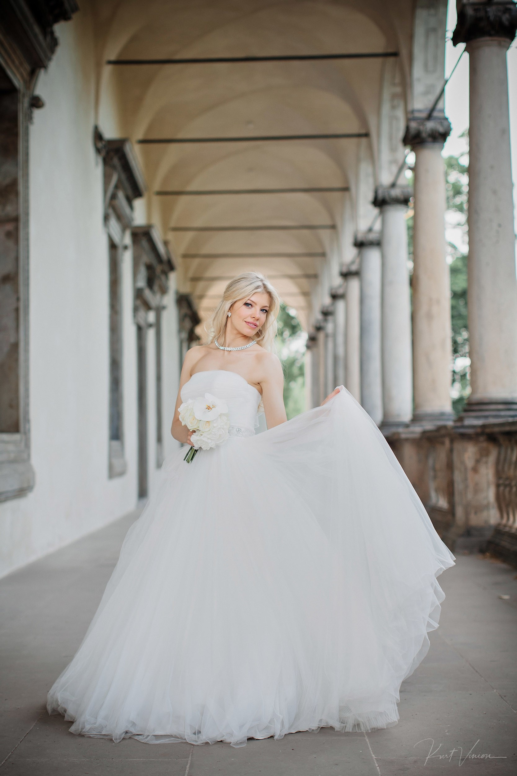 Bride posing confidently showing wedding dress at historic Prague palace